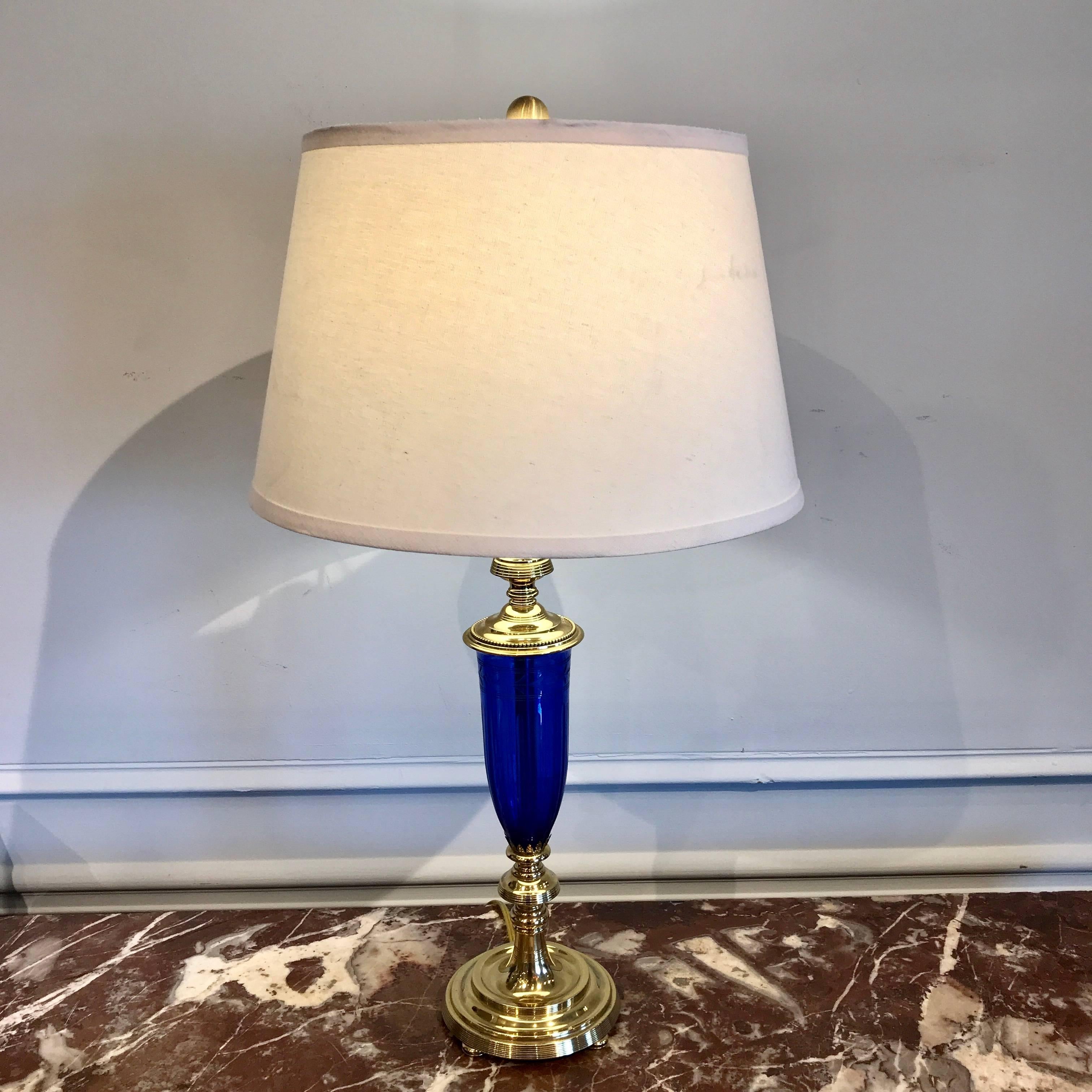 Pair of cobalt blue and brass-mounted urn lamps by Pairpoint, Each one with polished brass mounts, finely cut and engraved fluted cobalt blue urns. The lamp stands 19