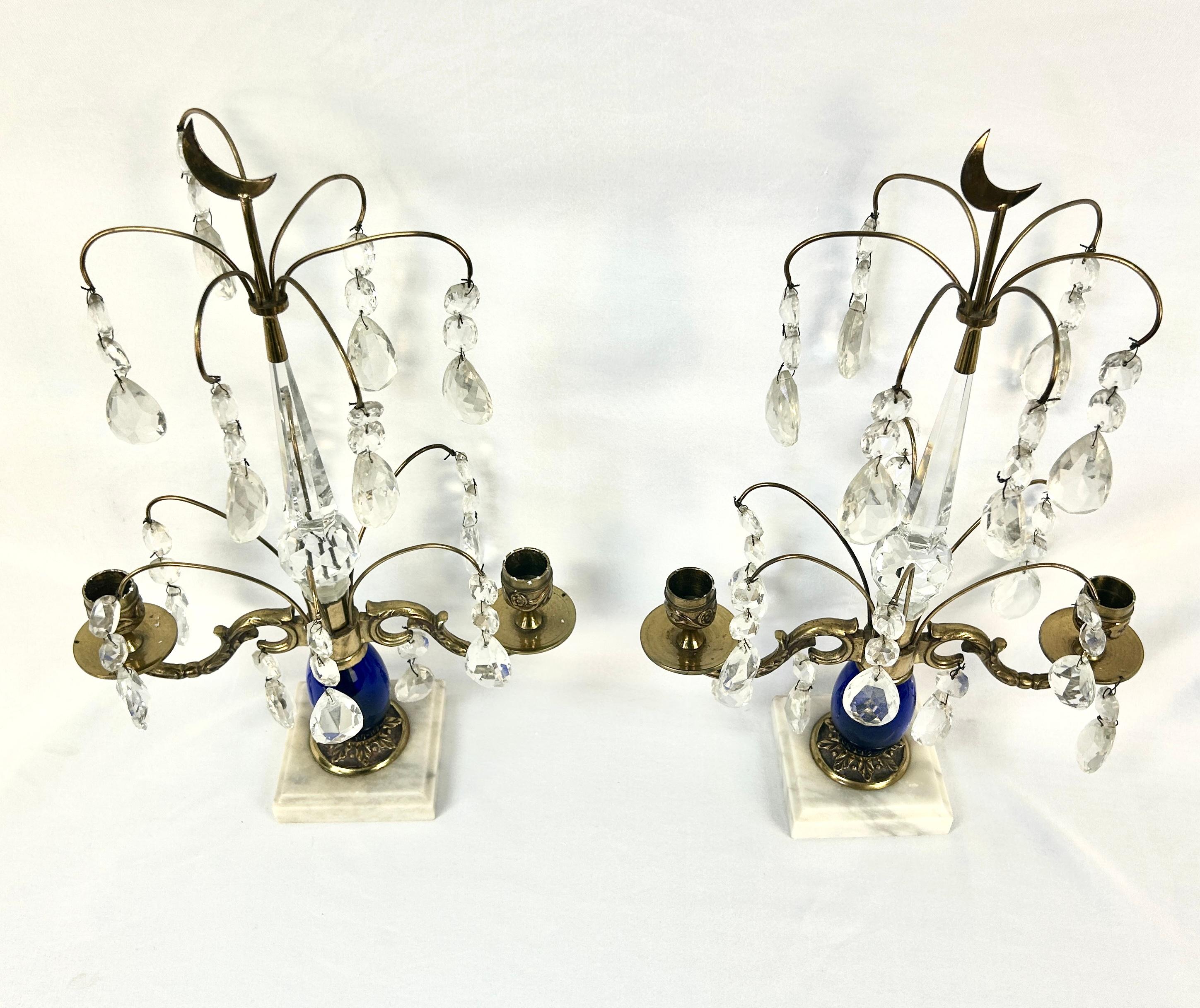 Pair of elegant Girandoles of Gustavian style, 19th century. Cobalt blue ovoid shafts resting on a white marble base. Each has two brass candleholders with delicate brass stems holding hanging antique crystals and topped by brass crescent moons.