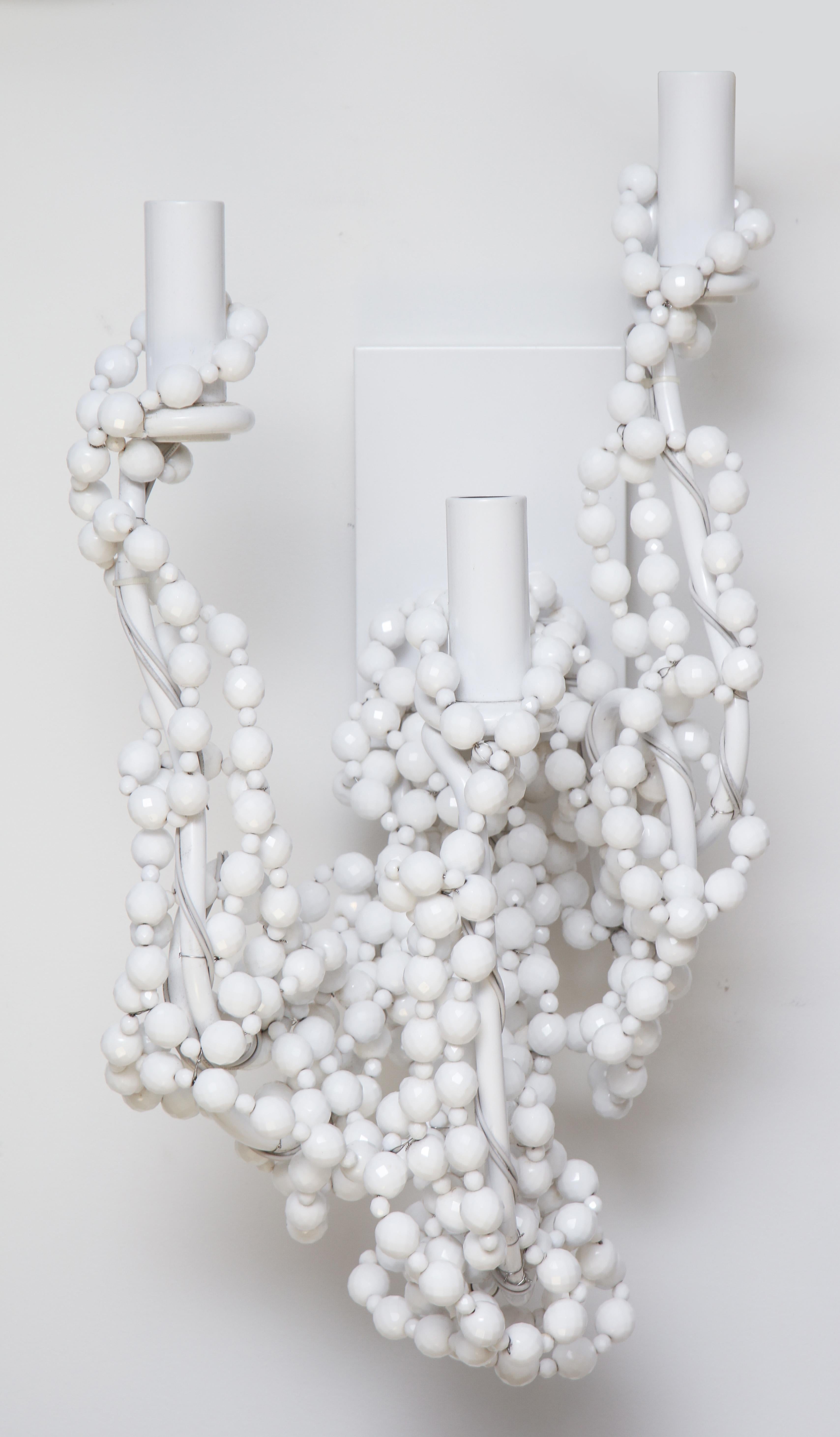 Pair of whimsical sconces by Brand Van Egmond.
Strings of white glass beads are wrapped around the metal armature in a
spontaneous and playful way.
Each sconce has three candelabra light sockets.