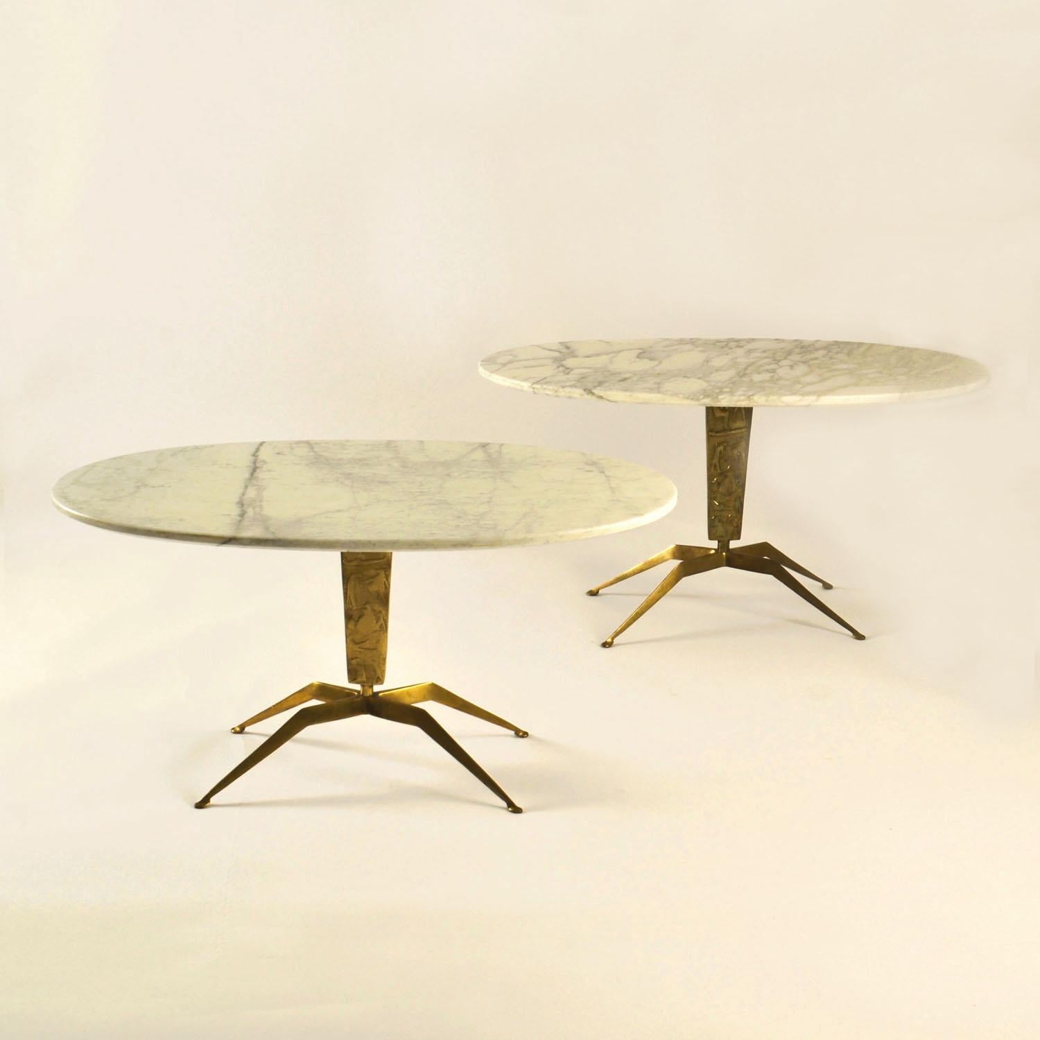 Paire de tables basses ovales avec plateau en marbre de Carrare soutenu par une base en laiton moulé sculptée d'un relief de personnages et reposant sur quatre pieds en forme d'araignée sur des pieds ovales. Les figures de la jambe sont abstraites