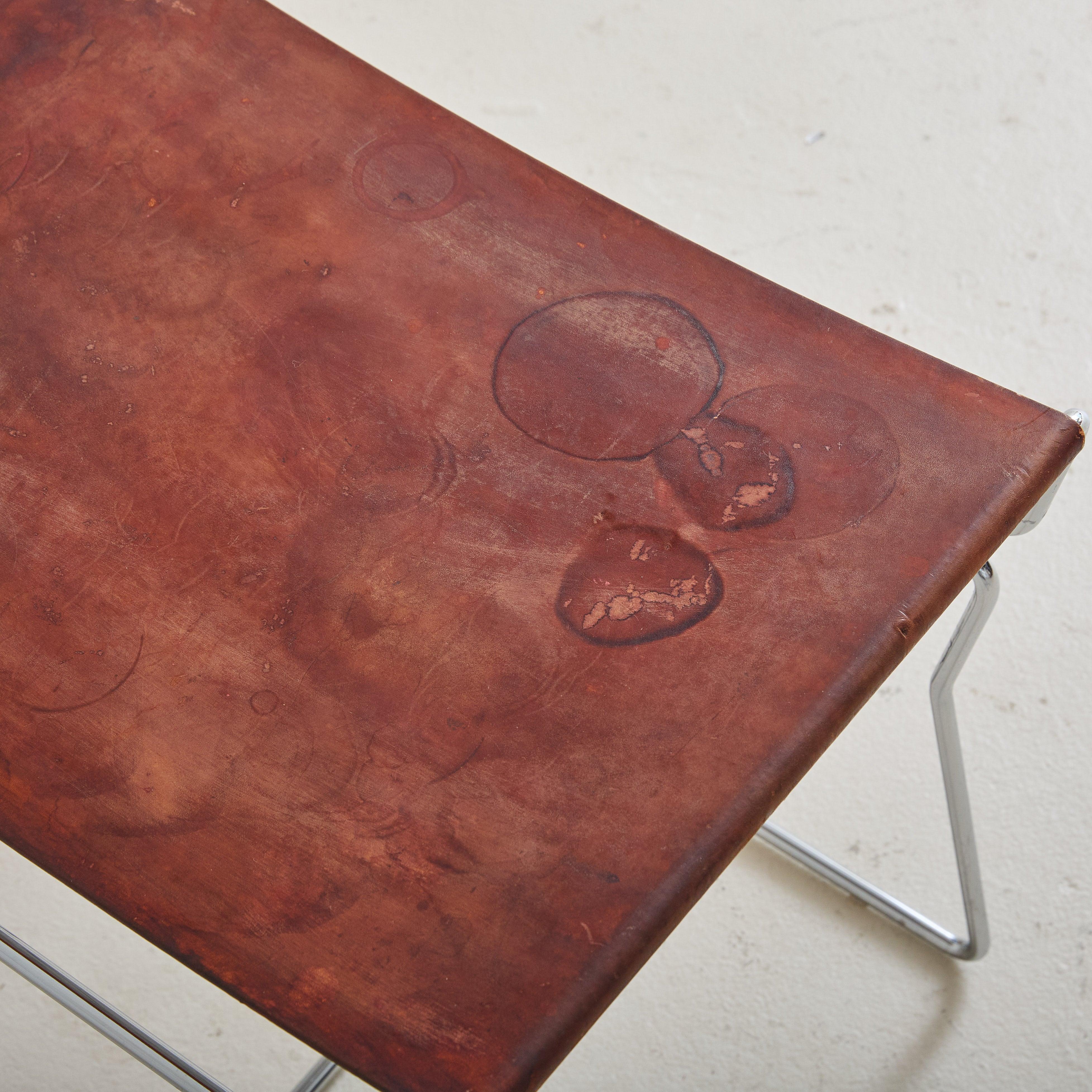 The ‘Pyllon’ stool, created by Nicole Aebischer in 2004 for industry pioneers B&B Italia, features a sleek chrome-plated steel frame topped with luxurious, thick cognac leather. Designed with a low profile, it's perfect for any space that requires a