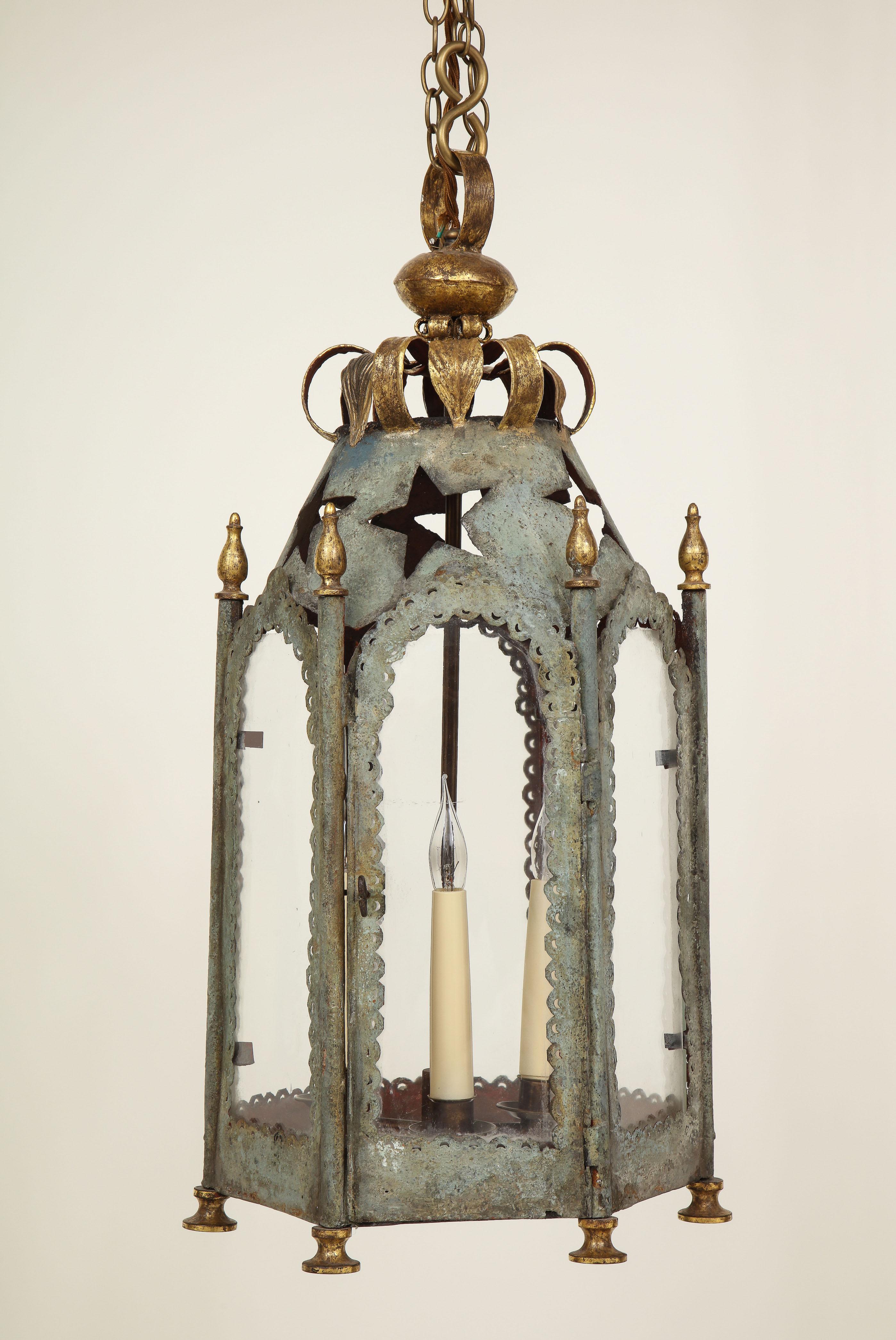 Each glass-paned hexagonal lantern with a patinated silver surface and pierced with stars; surmounted by a gilt foliate corona.