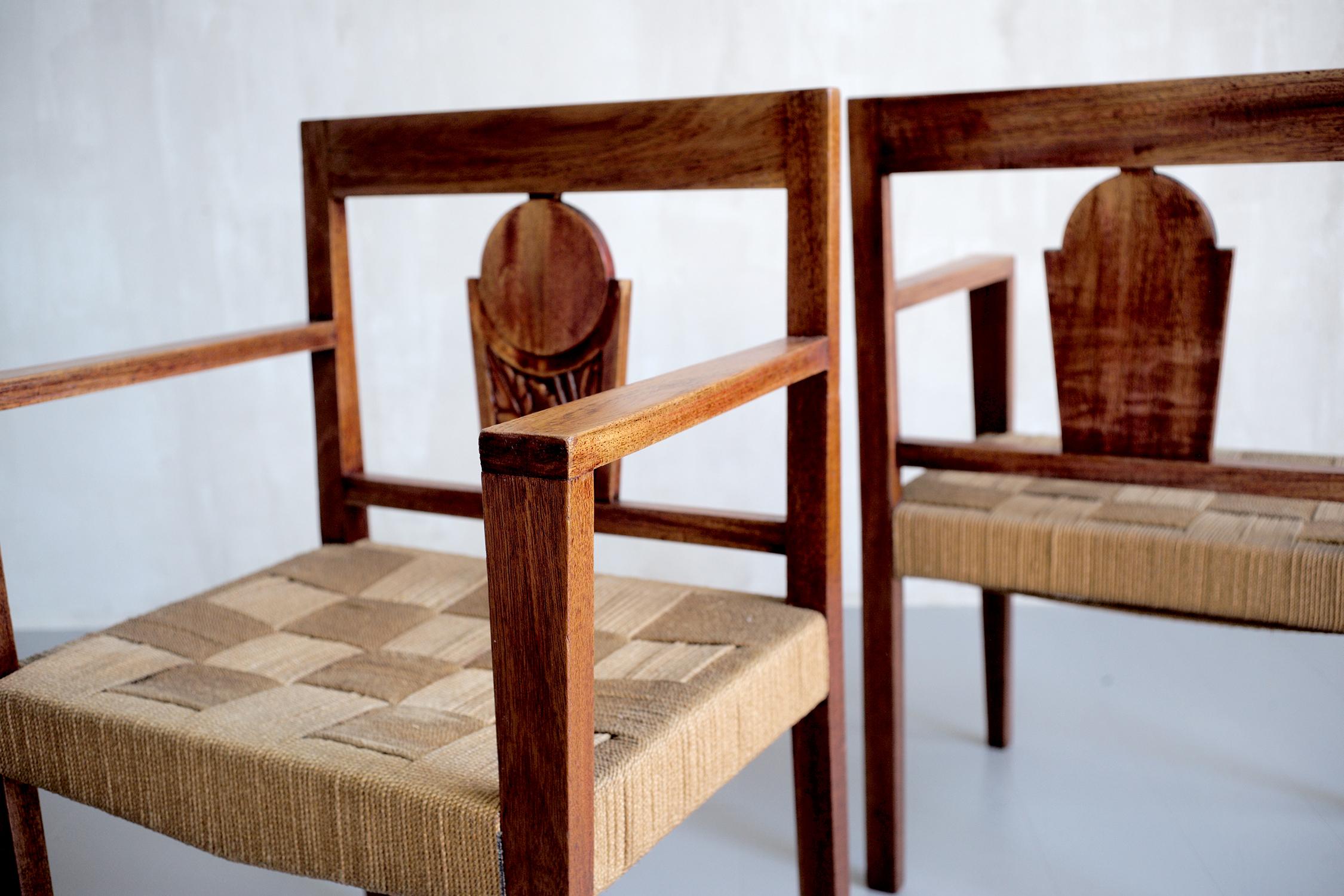 Pair of colonial armchairs in exotic wood, Africa, 1950. The backs are decorated with a sculpture with a floral motif, the seat is in crossed rope.