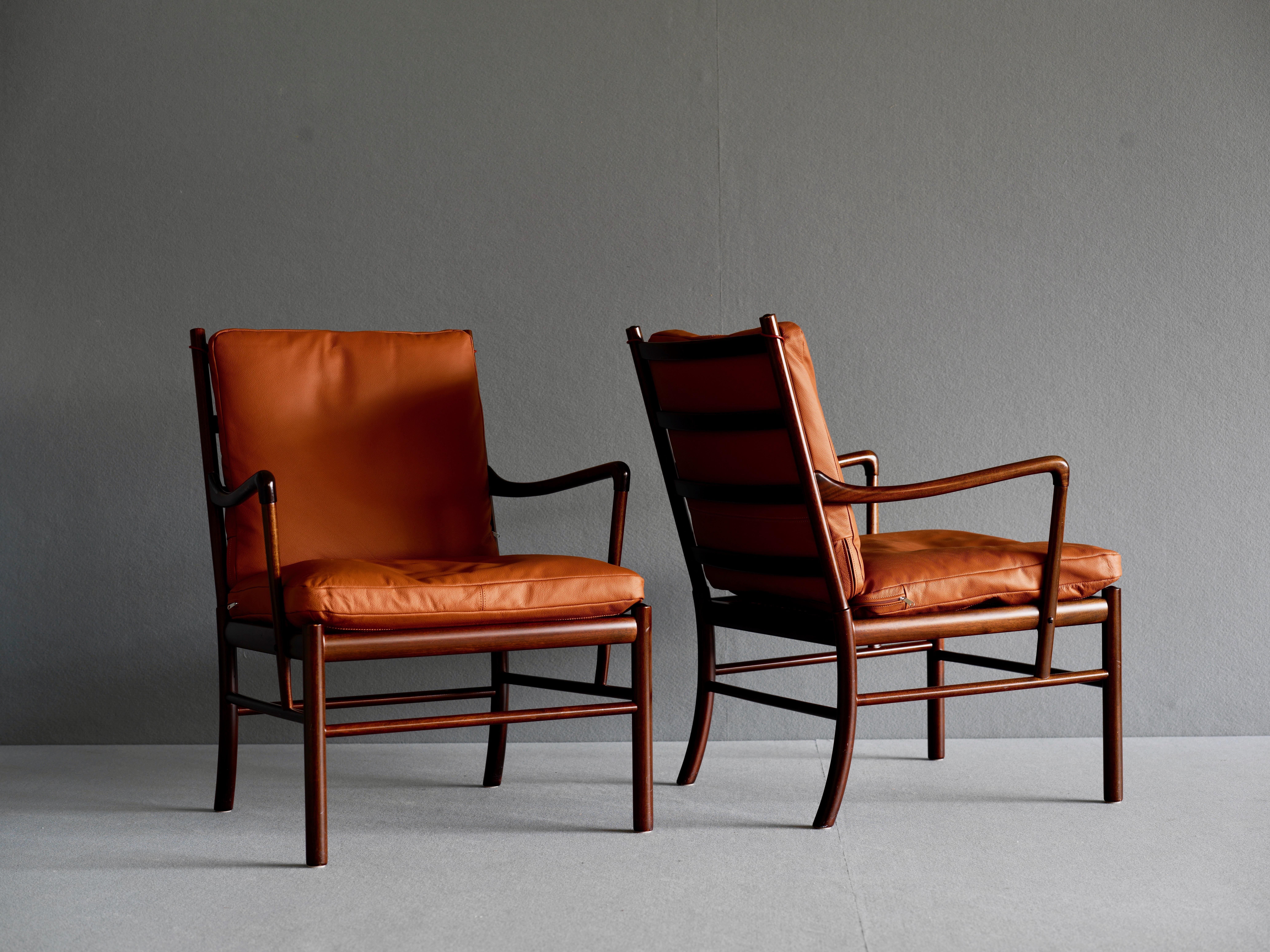 Pair of “Colonial” armchairs by Ole Wanscher for P Jepperson. They have a mahogany frame and a woven rattan cane seat. The cushions on the seat and back are upholstered in cognac leather. These chairs are elegant and refined in expression featuring