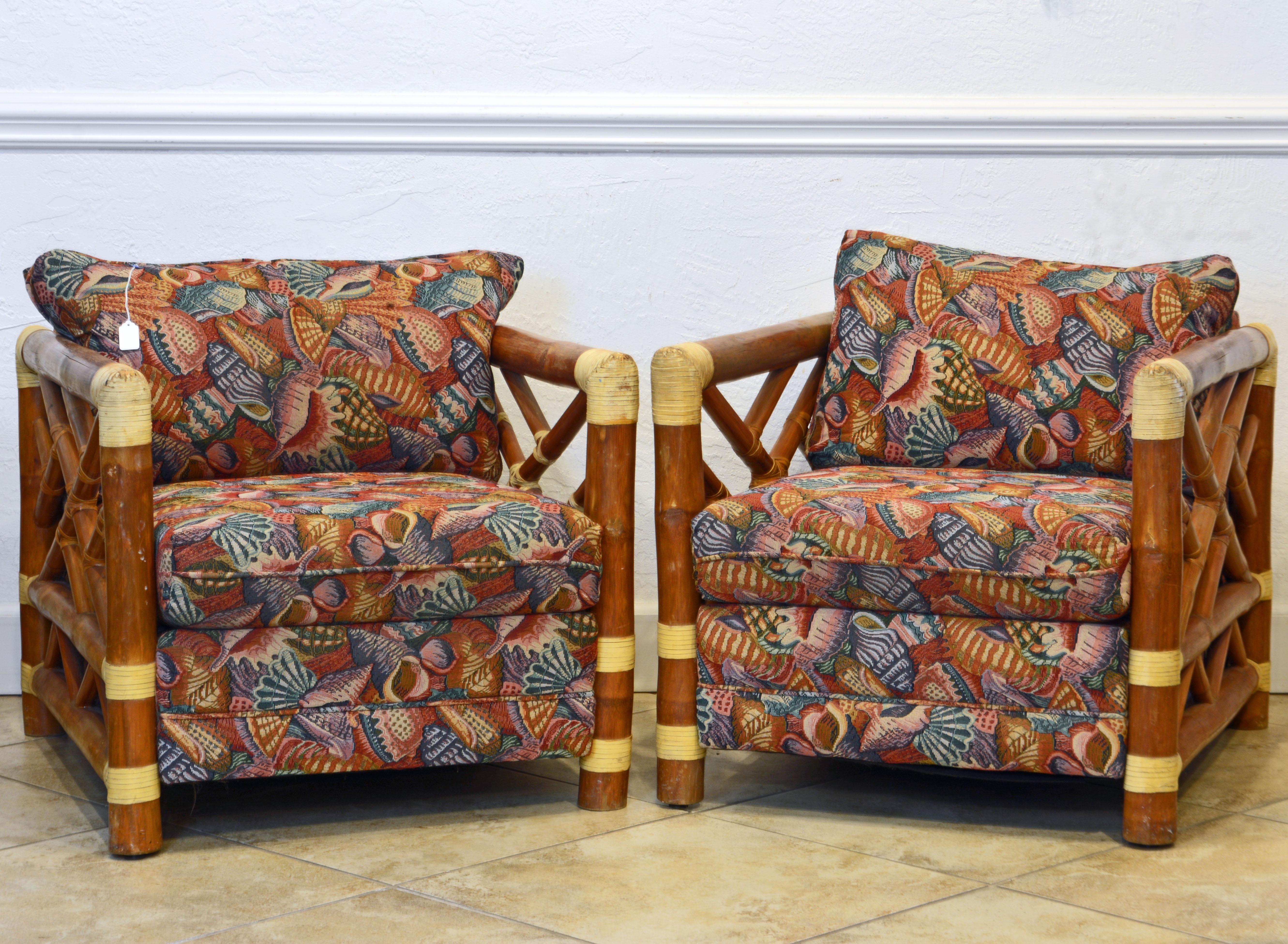 A pair of vintage colonial and tropical style bamboo pole lounge chairs of generous proportions, dating to the 1970s, upholstered with loose cushions and back pillows. The fabric strikes a coastal note with shells and sea elements. The chairs are