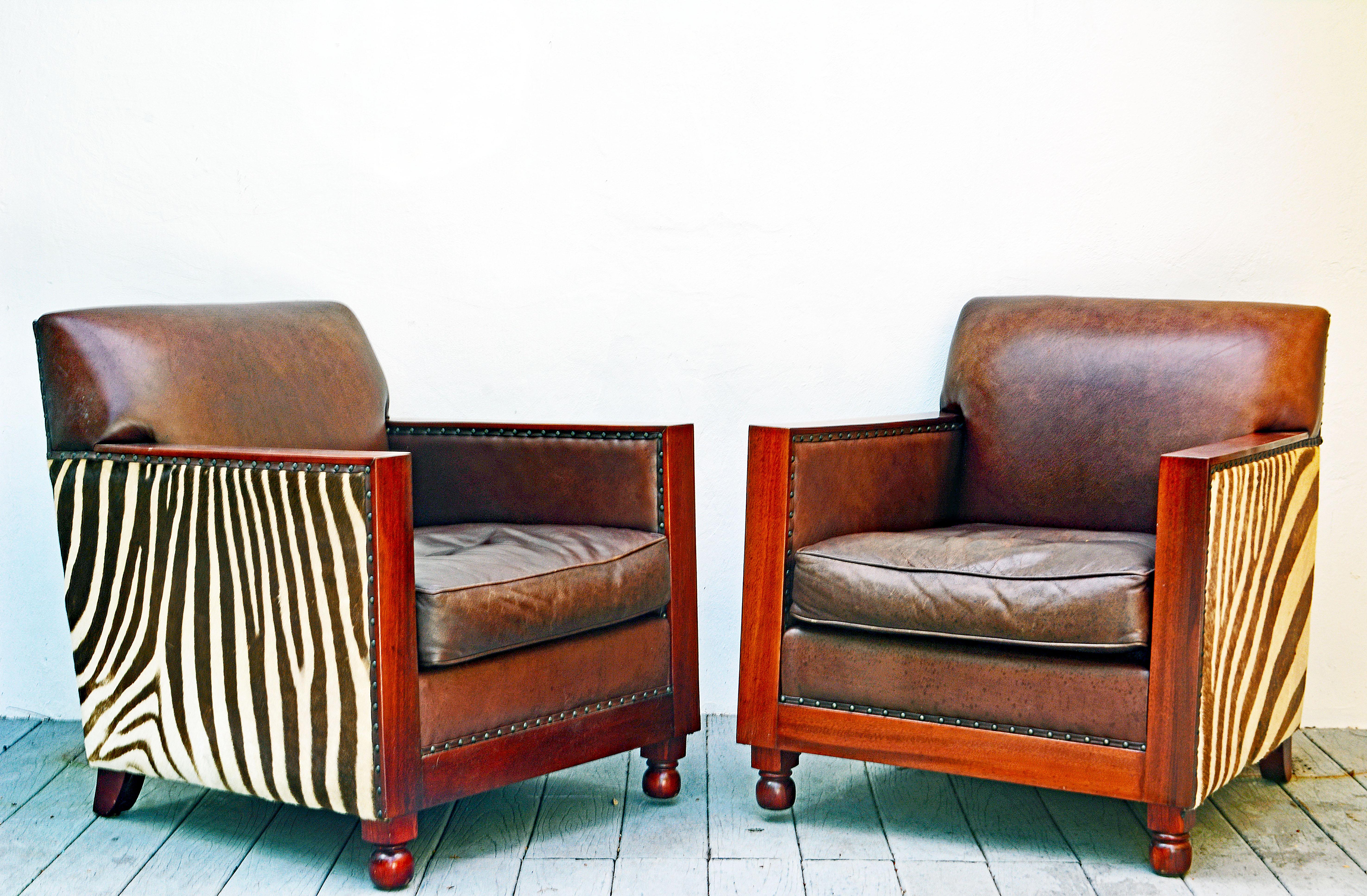 This pair of British Colonial style art deco inspired club chairs feature the very best craftsmanship and materials. The select zebra skin covered sides have great patterns and are chosen from the parts of the hide. The leather covered seats,