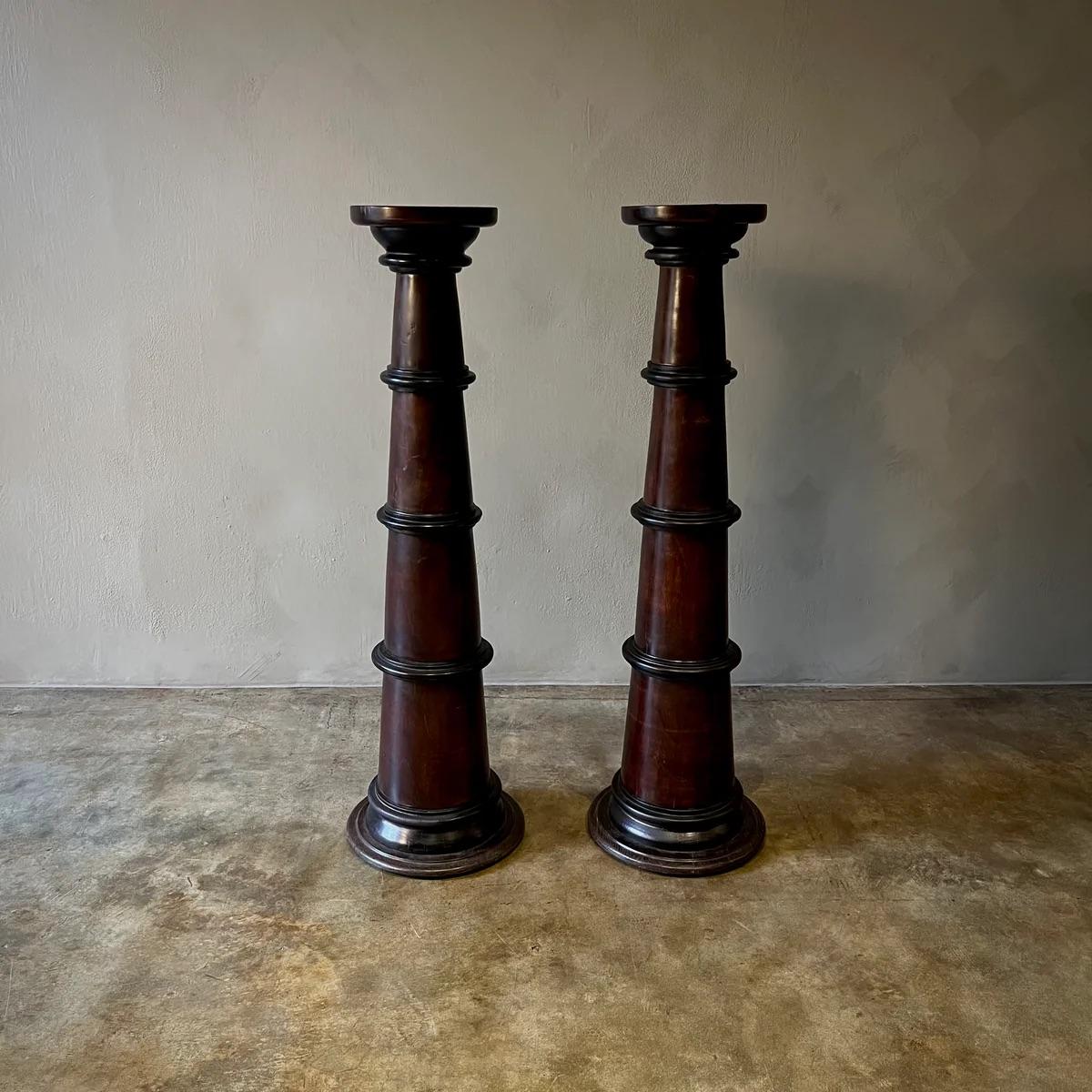 These commanding columns are crafted with a rich, dark stain that highlights their elegant, fluted design and substantial bases. The classic form lends itself well to traditional and contemporary spaces alike, offering a stately presence that can