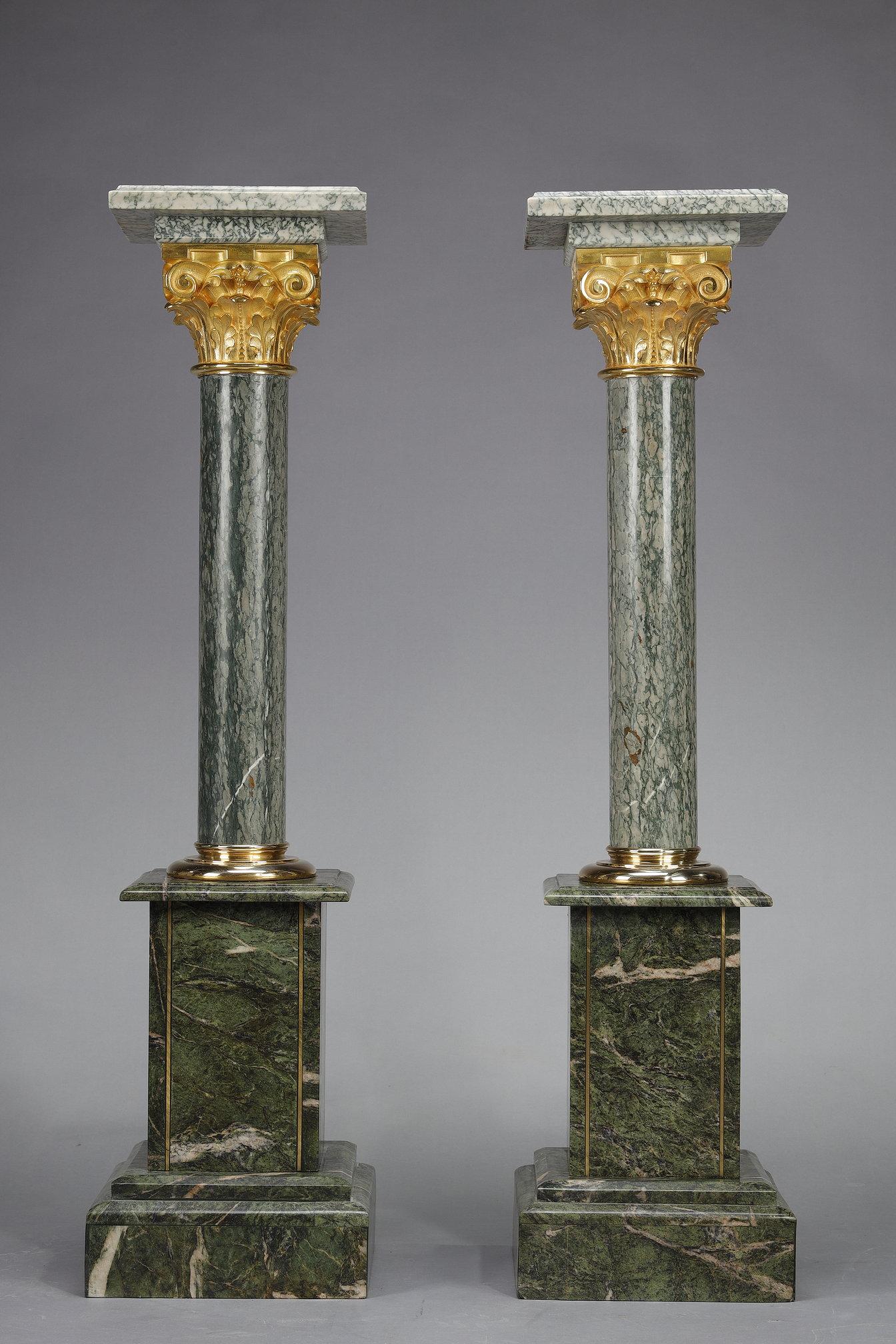 Ein Paar imposante Säulen aus grünem Estours-Marmor, gekrönt von einem korinthischen Kapitell aus vergoldeter Bronze und einer quadratischen Platte aus Estours-Marmor, ebenfalls 28 cm / 28 cm. Jede Säule ruht auf einem Sockel aus alpengrünem Marmor