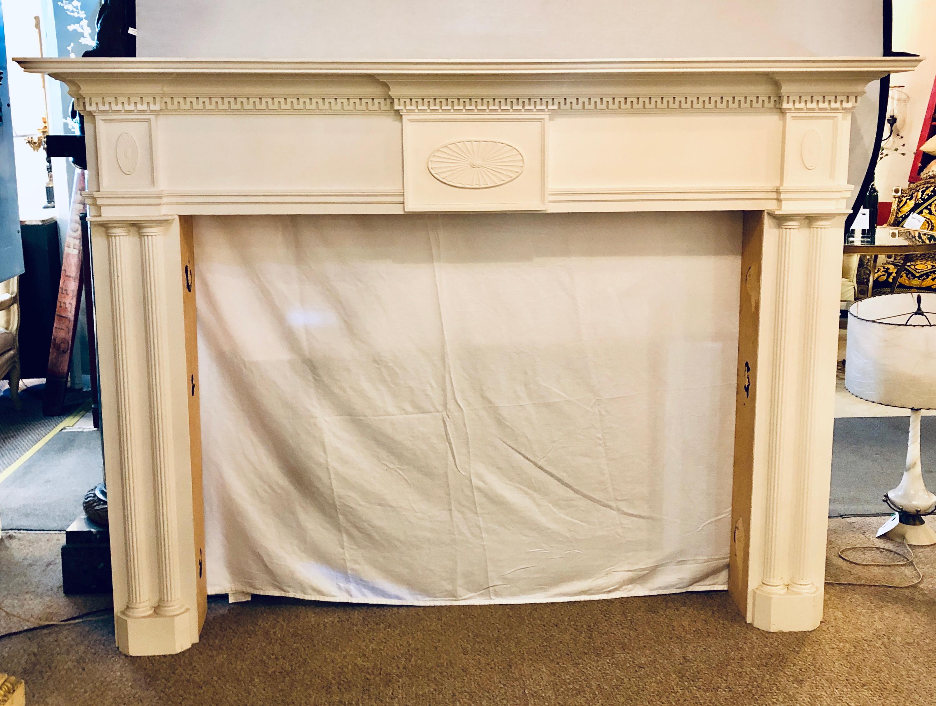 A monumental custom quality solid wood hand carved neoclassical fire place surrounds. This is a simply stunning piece in an off linen white painted finish with hand carvings throughout and urn form decorated. The whole with dental carvings under the