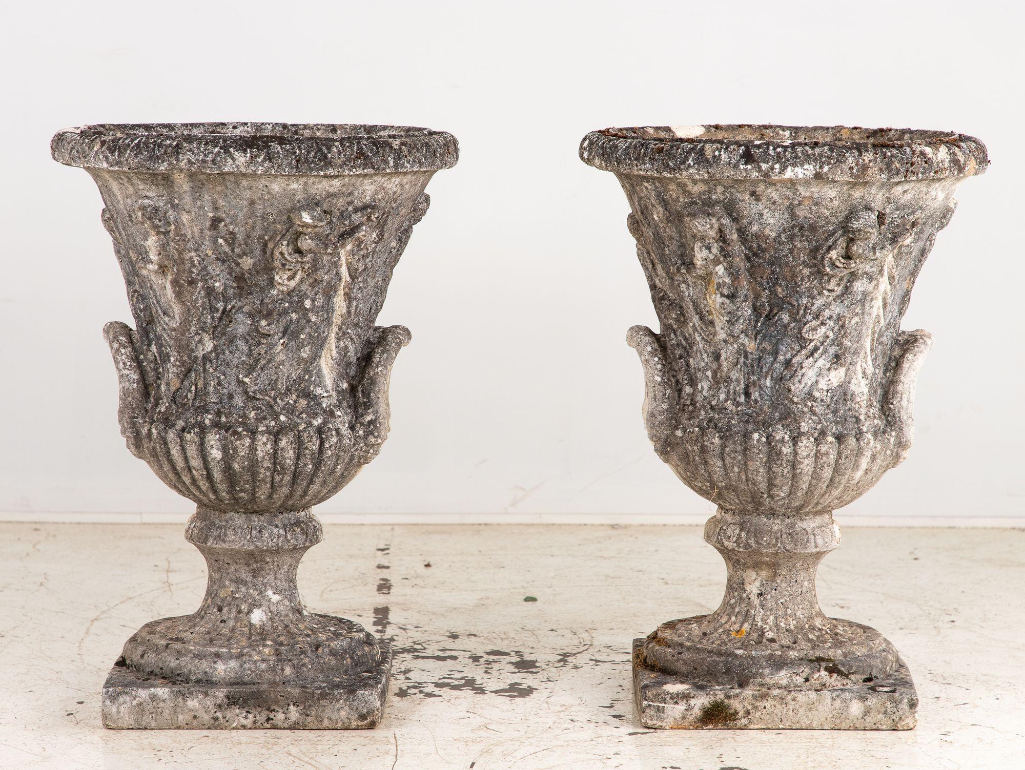Une paire frappante d'urnes en pierre de béton anglaises du début du 20e siècle rappelant le style d'Andrew Handyside. Les larges lèvres présentent un motif intemporel en forme d'œuf et de fléchette, tandis qu'une série de figures en mouvement
