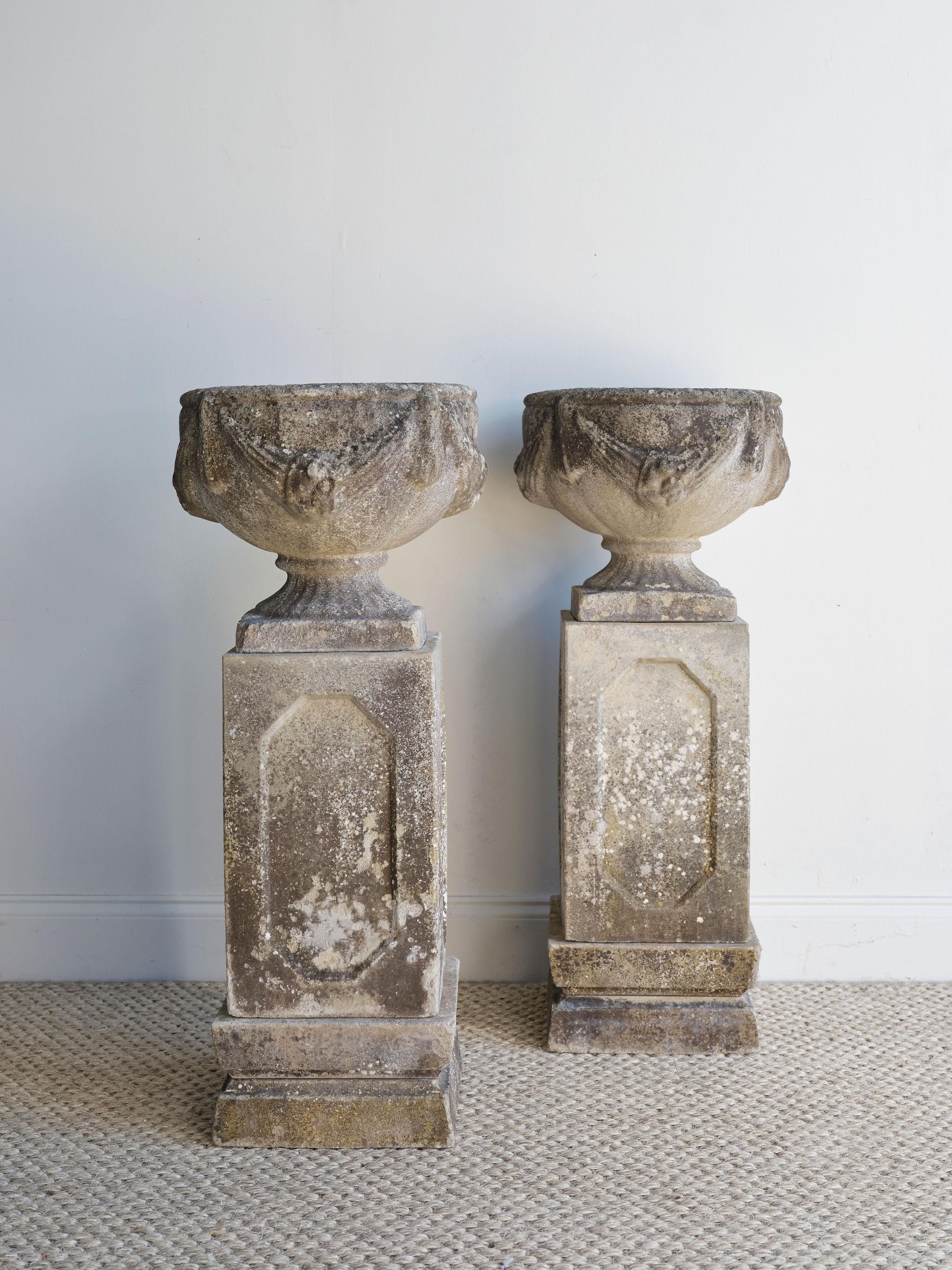 These beautiful concrete swag urns were created in 19th century England. They are extremely heavy and each urn comes with 4 pieces total. So for the pair, the total number of pieces would be 8. The concrete is weathered, but still in great condition.