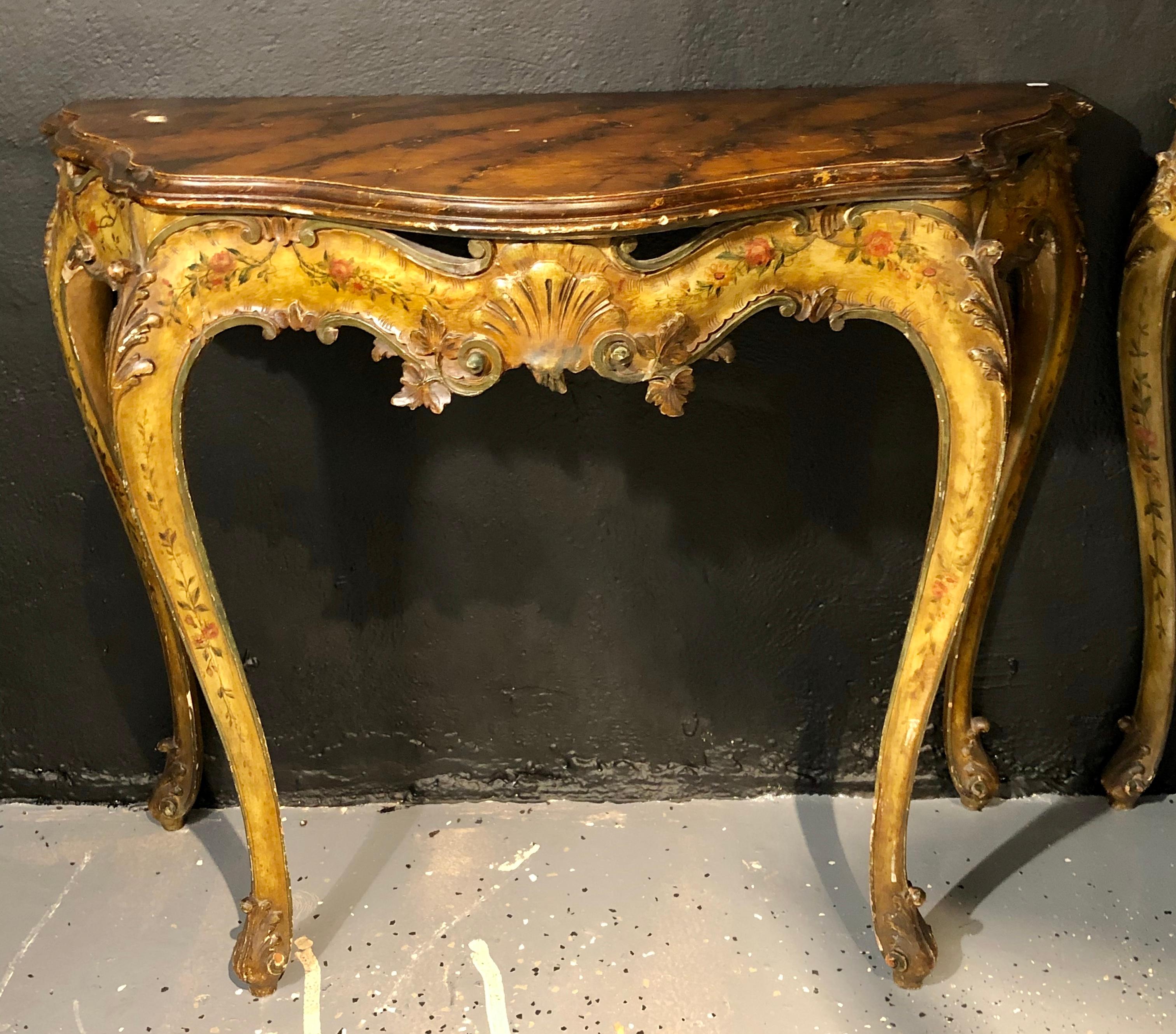 Pair of console table Italian paint decorated bases on faux marble top. This stunning pair of late 19th-early 20th century console tables have serpentine form in the Louis XV style with floral painted shell carved bases supported a fine faux marble
