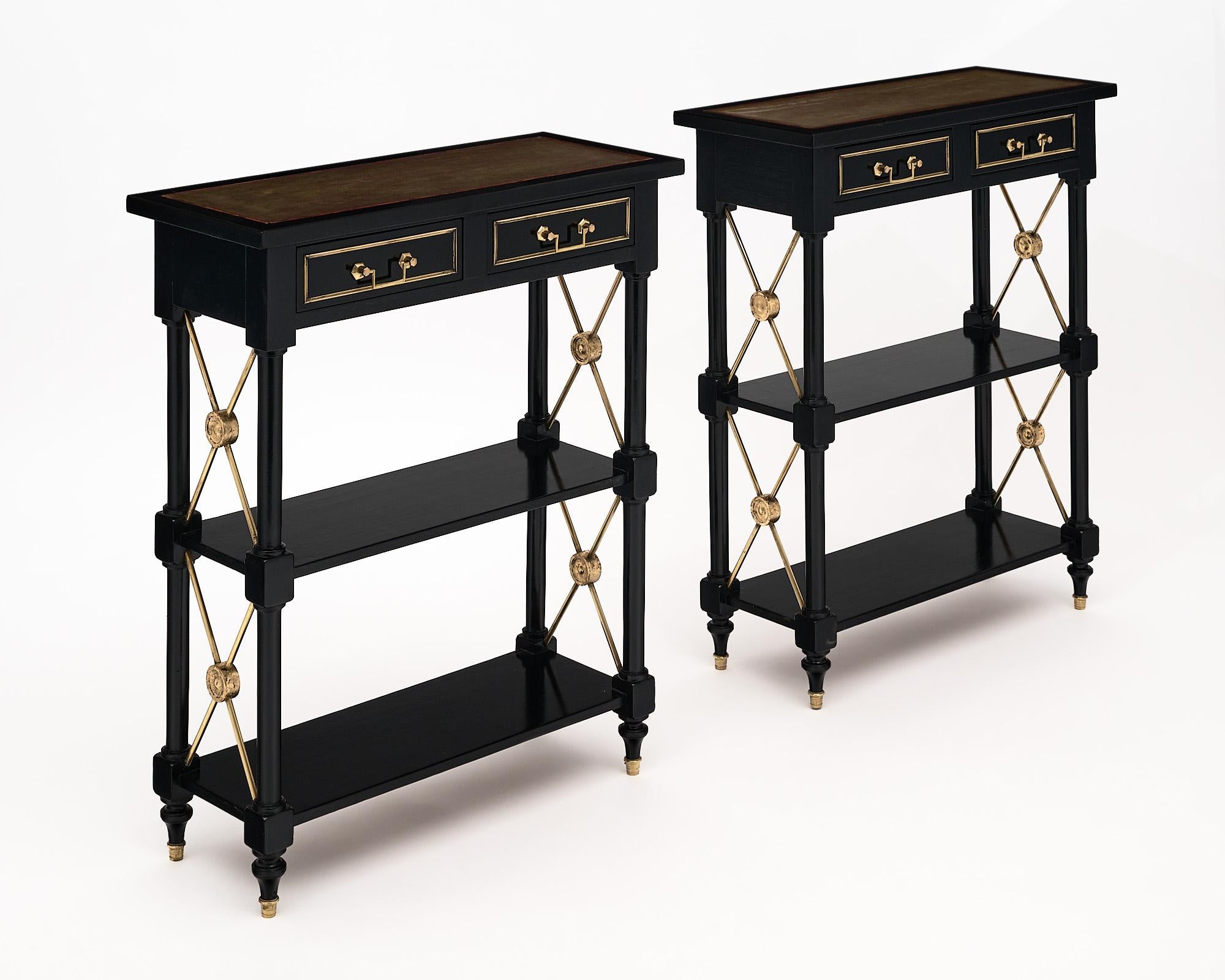 Pair of console tables, French, by Maison Jansen made of Mahogany, ebonized and French Polished. Each side table features two dovetailed drawers with their original brass handles. The tops are original stained moleskin. Two wooden shelves are