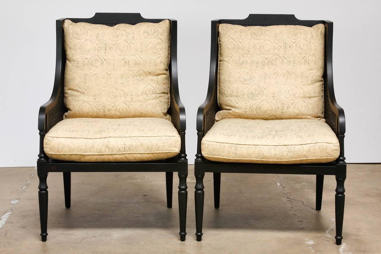 Stylish pair of contemporary black lacquer wingback chairs. Featuring a wooden frame with double caned walls on the sides and back. Each made with generous proportions in the English Regency style with graceful arms and turned legs. The arms measure
