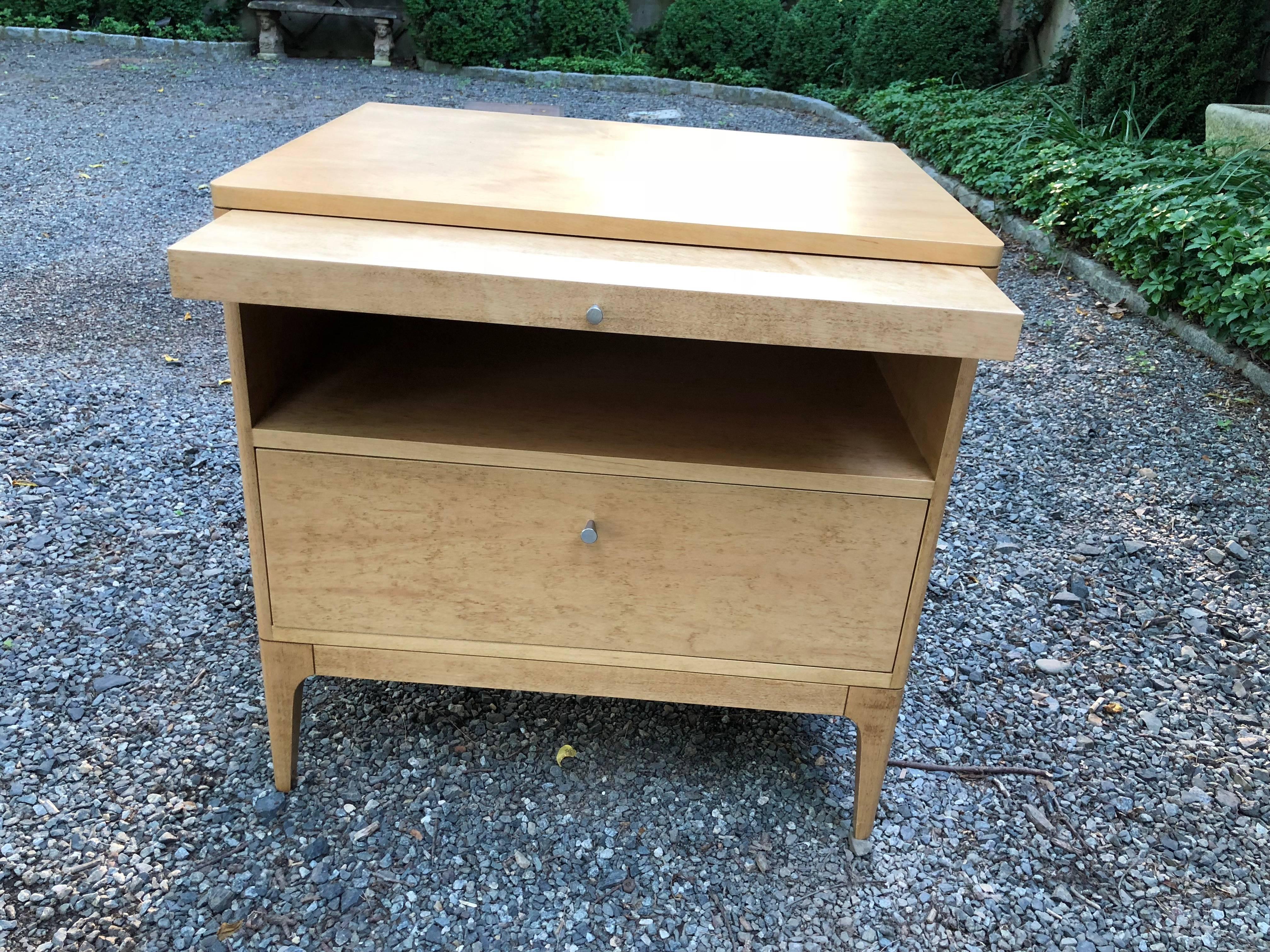 Sleek pair of blonde wood nightstands or end tables attributed to Barbara Barry. Each has one drawer, a stationary shelf and a pullout shelf that slides. Hardware is in a brushed silver. No makers tags. The pullout shelf is 15 deep x 24.5