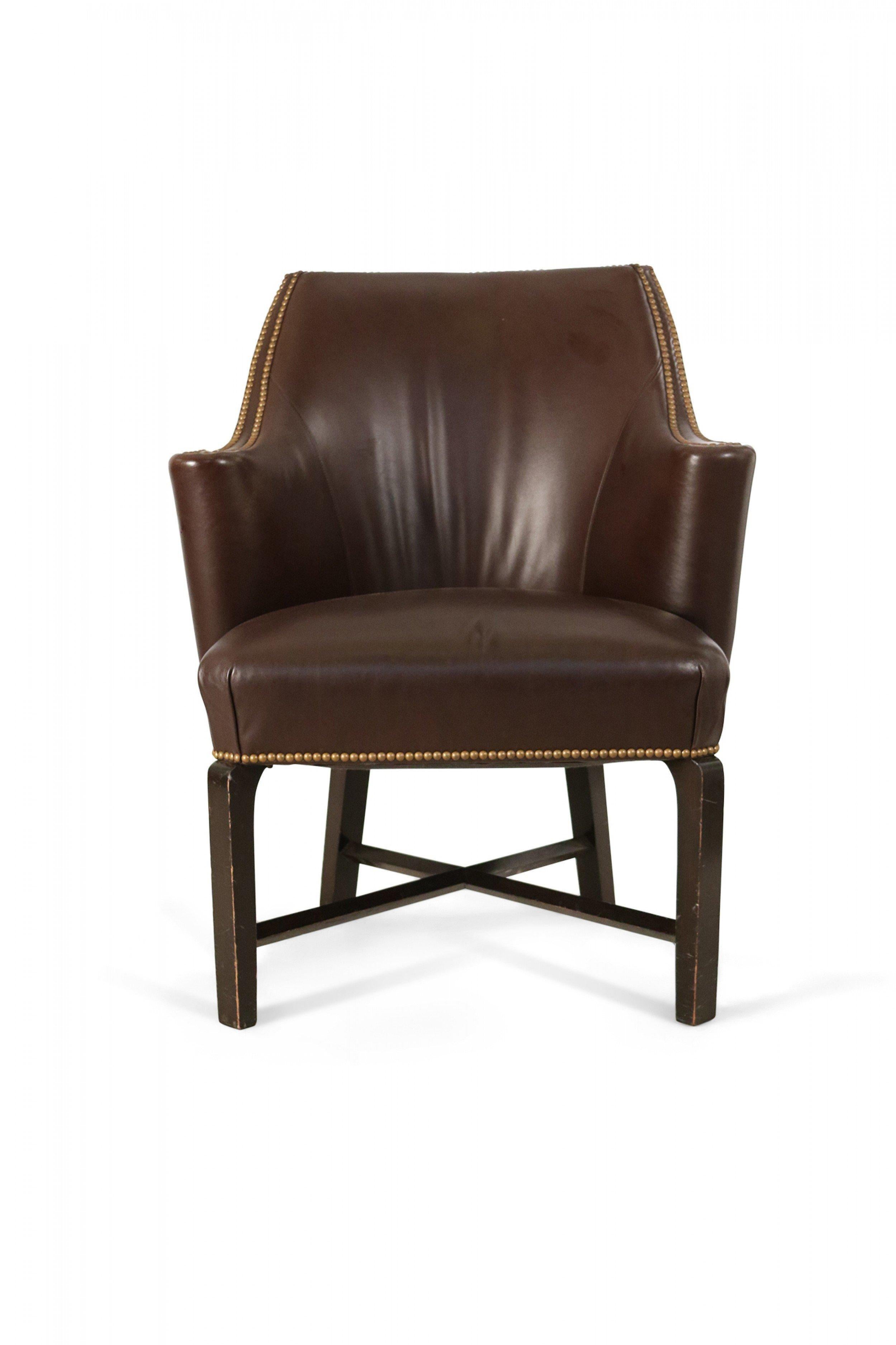 Pair of Contemporary brown leather club / armchairs with rounded backs, black painted wooden legs with an x-shaped stretcher, and brass upholstery nail detail. (PRICED AS PAIR).