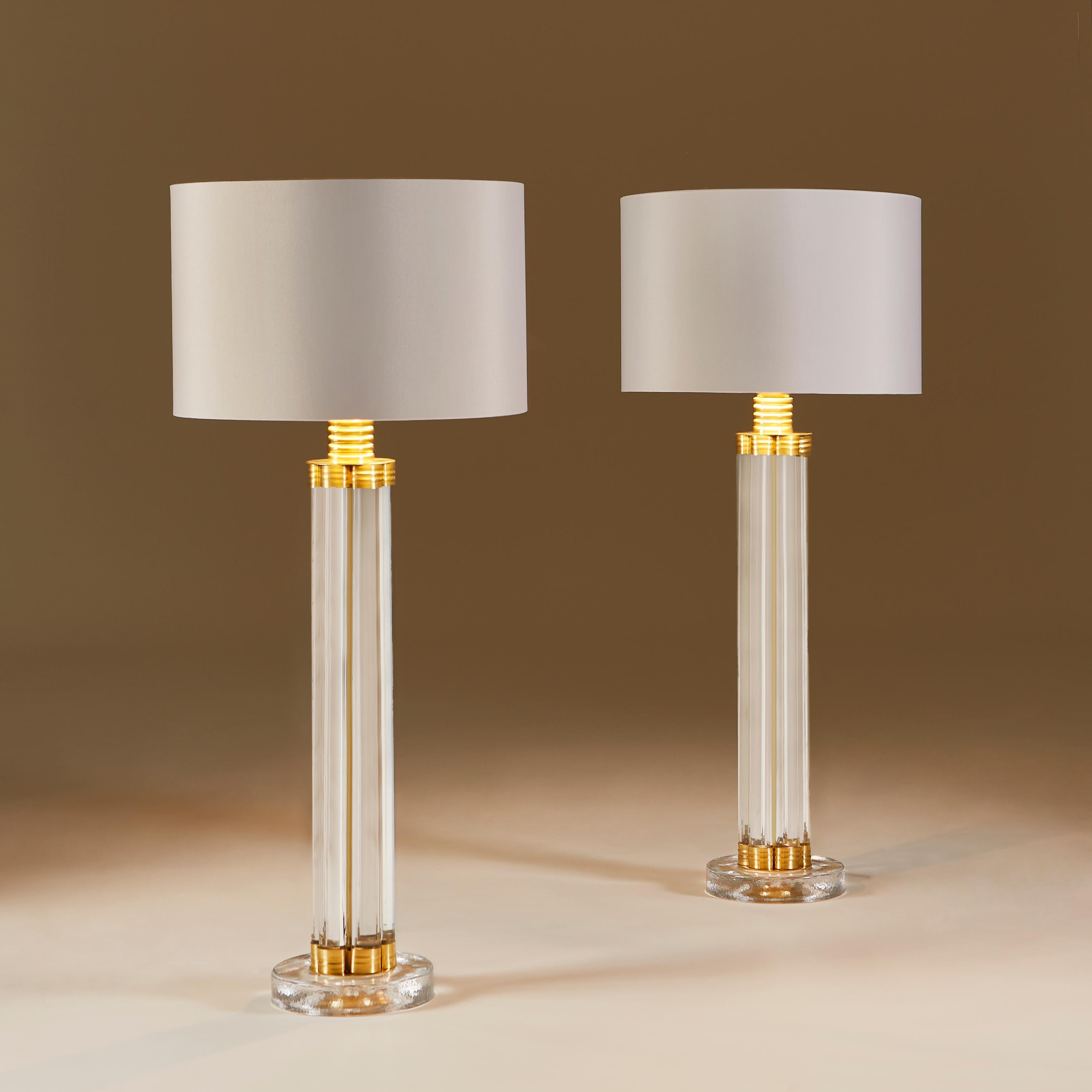Striking contemporary pair of table lamps each made of six vertical glass rods held together at the top and bottom with decorative brass elements, standing on heavy square glass bases with rounded edges.