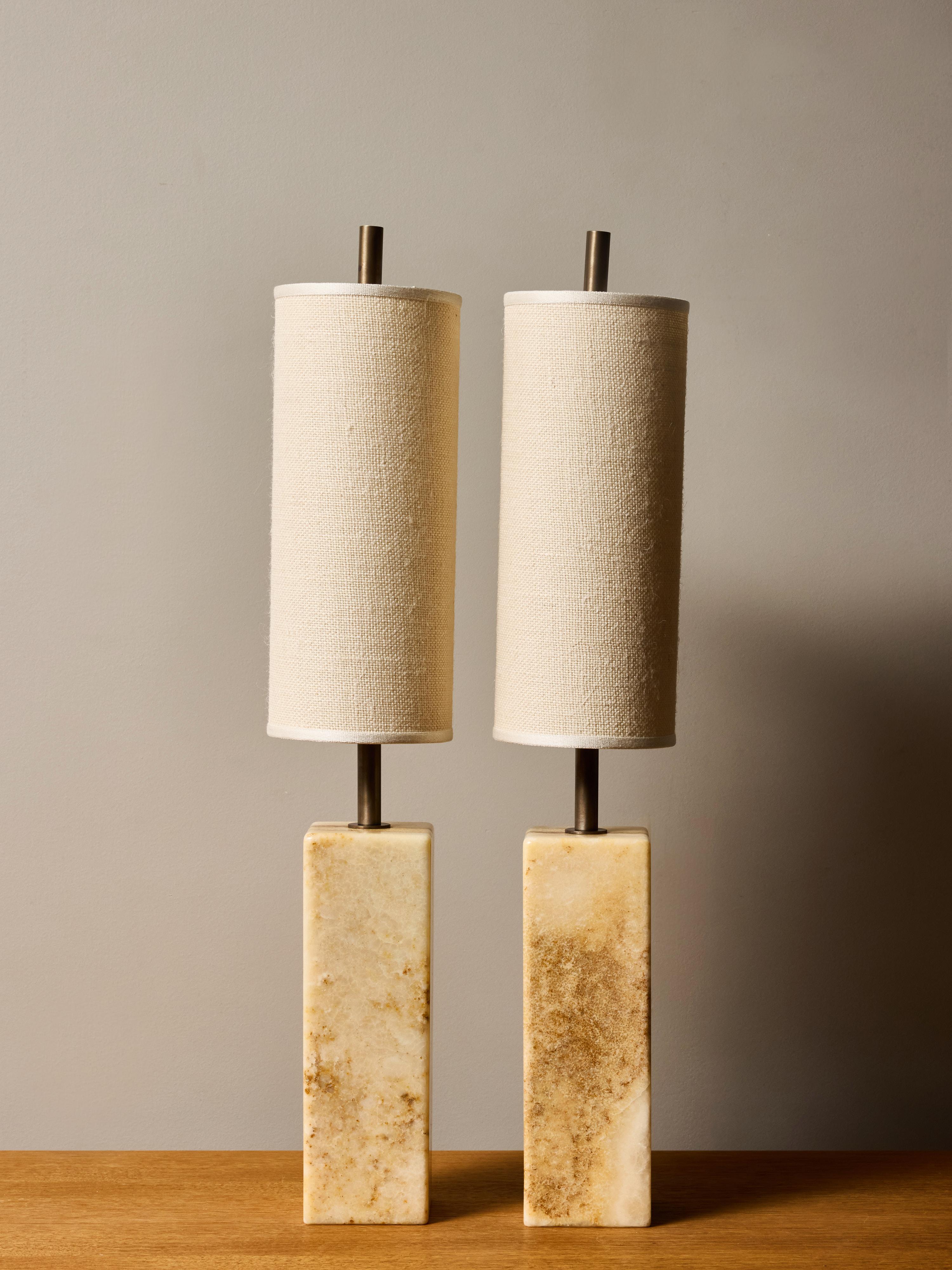 Dieses elegante Paar zeitgenössischer Tischlampen verfügt über geschnitzte Marmorsockel, die natürlich vorkommende Streifen in warmen Creme-, Sand- und Bernsteintönen aufweisen. Jeder skulpturale Block ist präzise geformt und hat sanft abgerundete