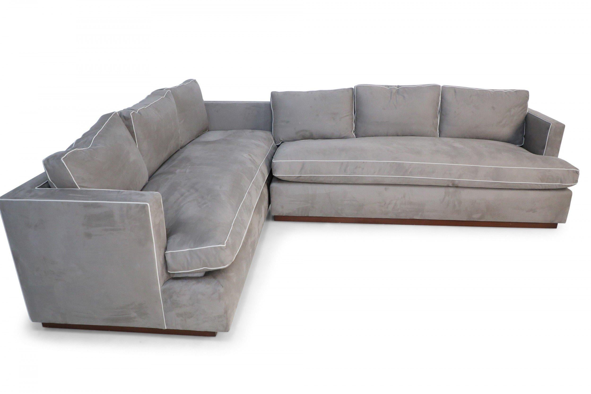 Contemporary overstuffed two piece sofa sectional with gray Ultrasuede upholstery with off-white piping, three back cushions and a single seat cushion on wooden bases (priced as set).