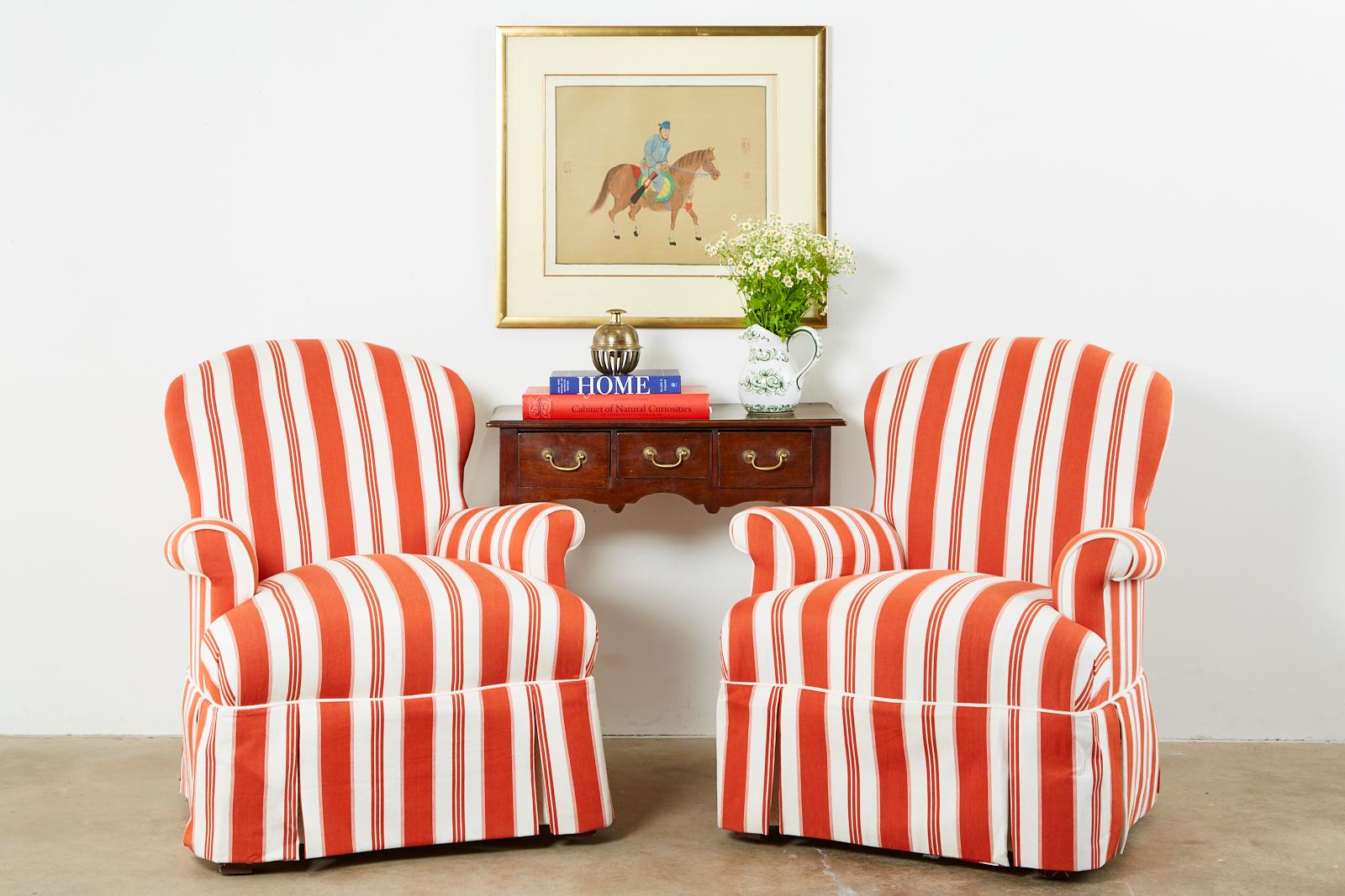 Whimsical pair of upholstered lounge chairs or club chairs featuring a striped fabric. Contemporary style with a hardwood frame. The generous seat has English style flared or rolled arms and is skirted. Like new with excellent joinery and