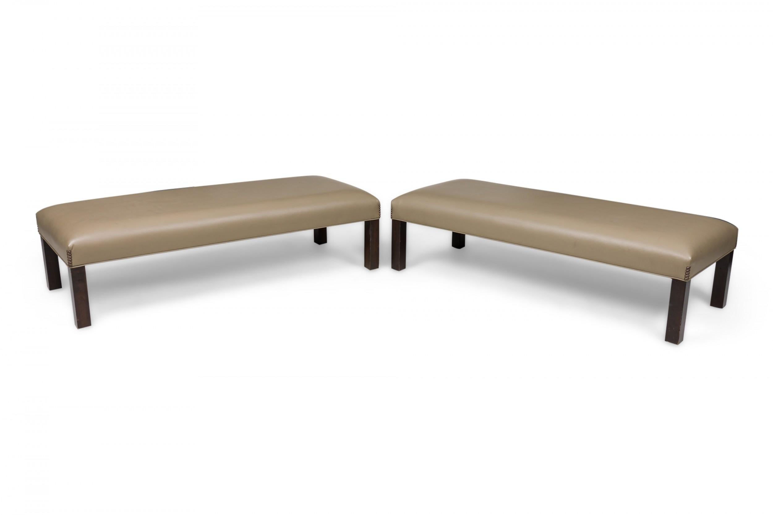PAIR of Contemporary rectangular benches with taupe leather upholstered tops with bronze upholstery nail detail on each corner, resting on four square wooden legs with a dark wood veneer. (PRICED AS PAIR).