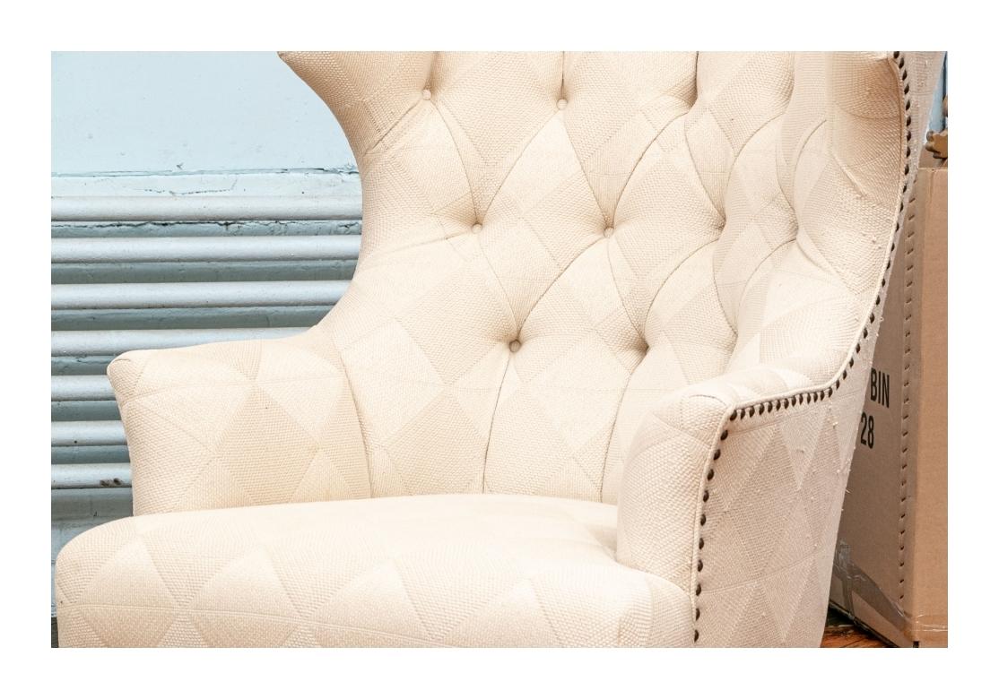 Large scale Wingback Lounge Chairs with angular wings and button tufted channelled backs. The dark stained wood frames raised on square front legs and square splayed back legs. Upholstered in a cream textured fabric in a diamond pattern. Quite