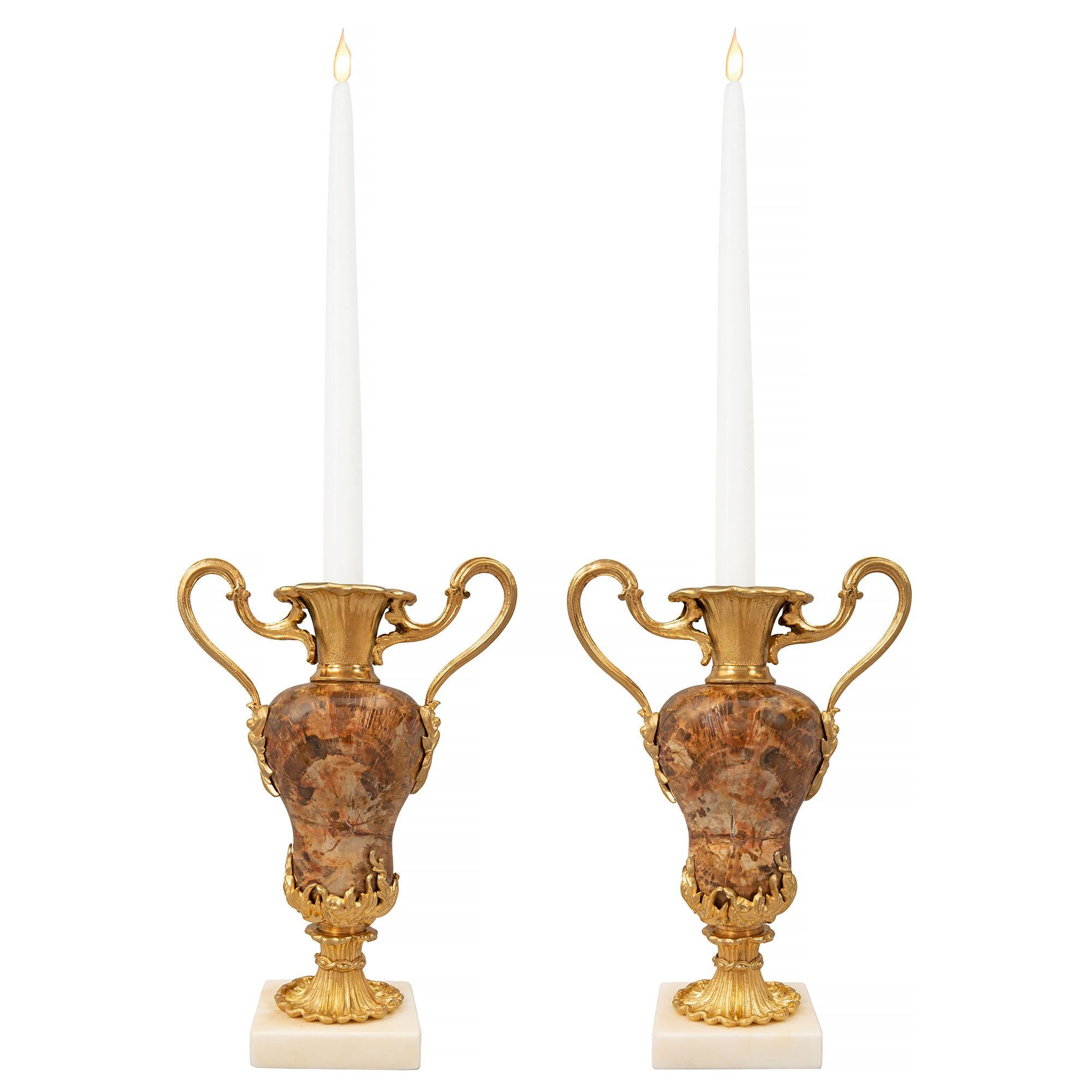 An exceptional and rare pair of Continental 19th century Louis XVI st. white Carrara marble, ormolu and petrified wood candlestick vases. Each vase is raised by a square white Carrara marble base and a lovely ormolu socle pedestal with an elegant