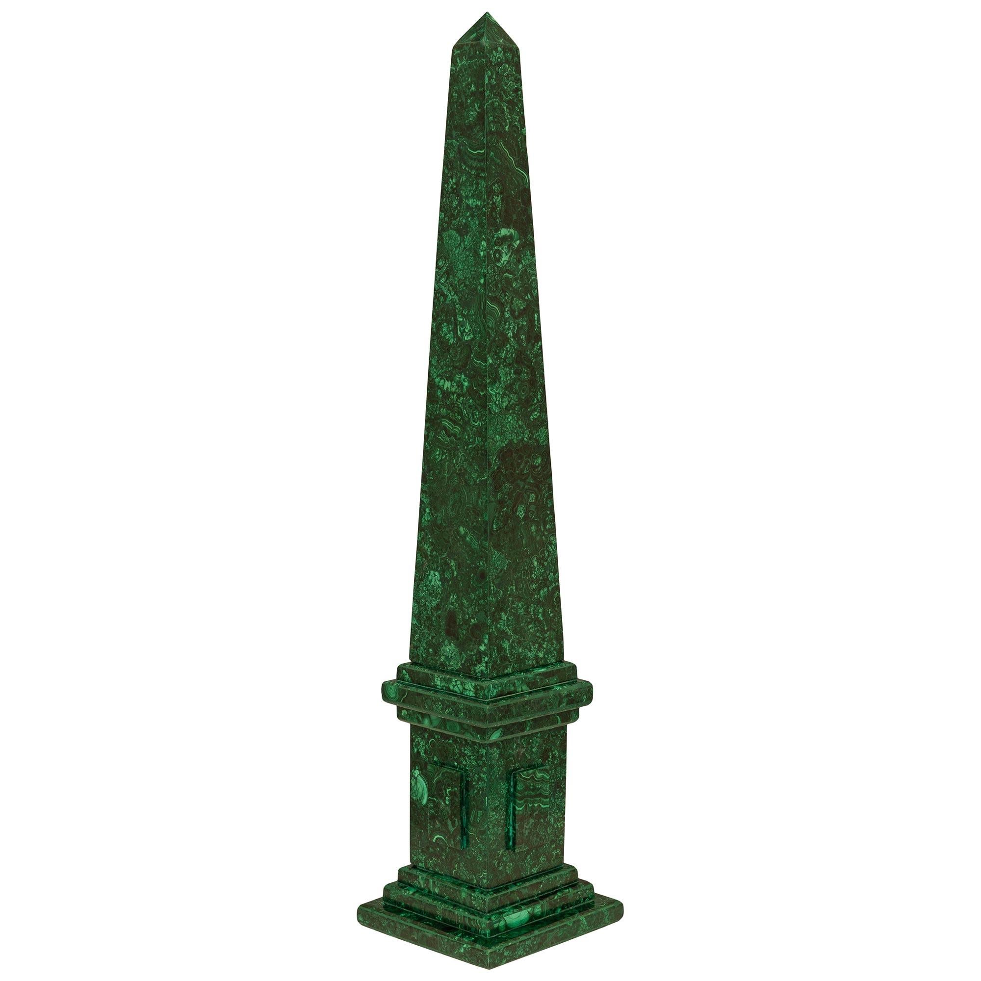 An impressive and very decorative pair of Continental 19th century Malachite obelisks. Each obelisk is raised on a square base with a mottled border. The Malachite stepped base supports the square plinth with raised panels leading up to the solid