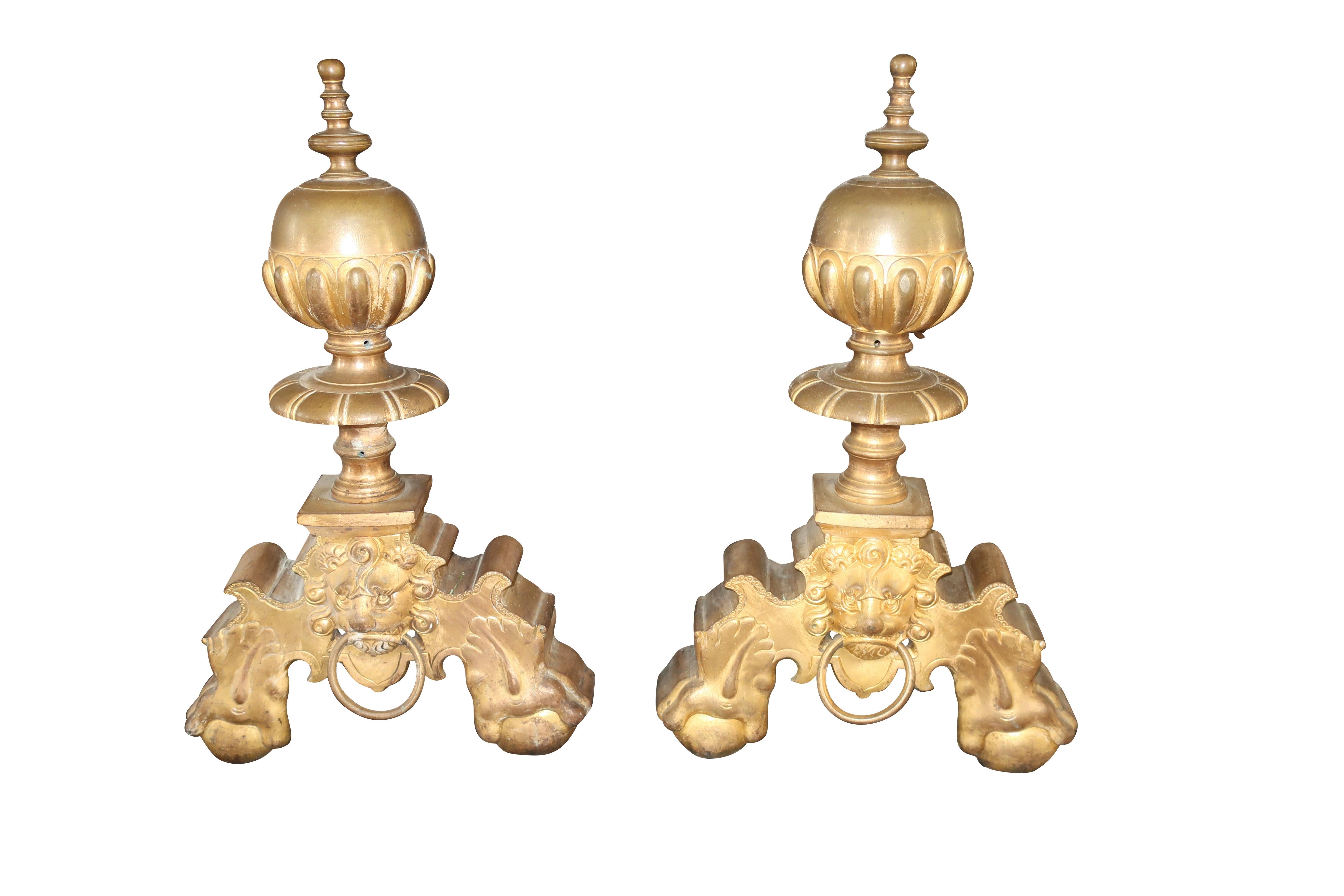 This exquisite pair of antique chenets/ andirons are made in France in the late 19th century. Created in a lustrous doré bronze, they feature lion head designs. The design adorns the center panel between the two legs. Excellent condition.