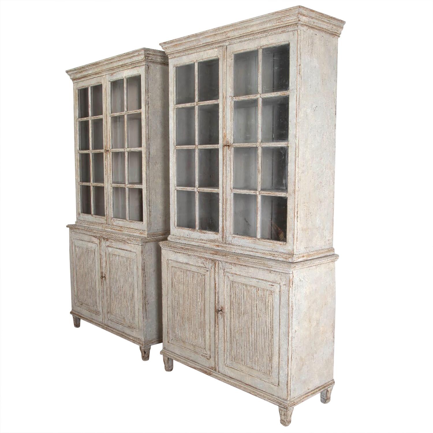 An exceptional pair of continental painted bookcases. Carved cornice with beading edge, with a pair of eight glazed paneled doors opening to storage shelves. Two further reeded doors open to further storage. These bookcases have tapered legs, 20th