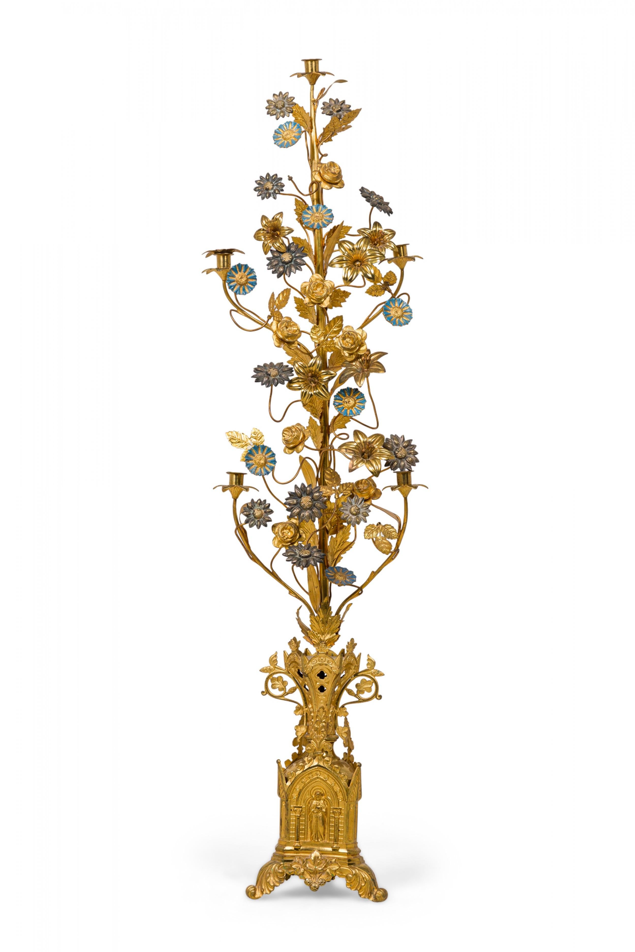 Pair of Continental (19/20th century) brass candelabras with central posts supporting a vine-like exterior embellishment structure with candle holders interspersed among blue enameled and antiqued brass flowers and leaves. The bases are three-sided