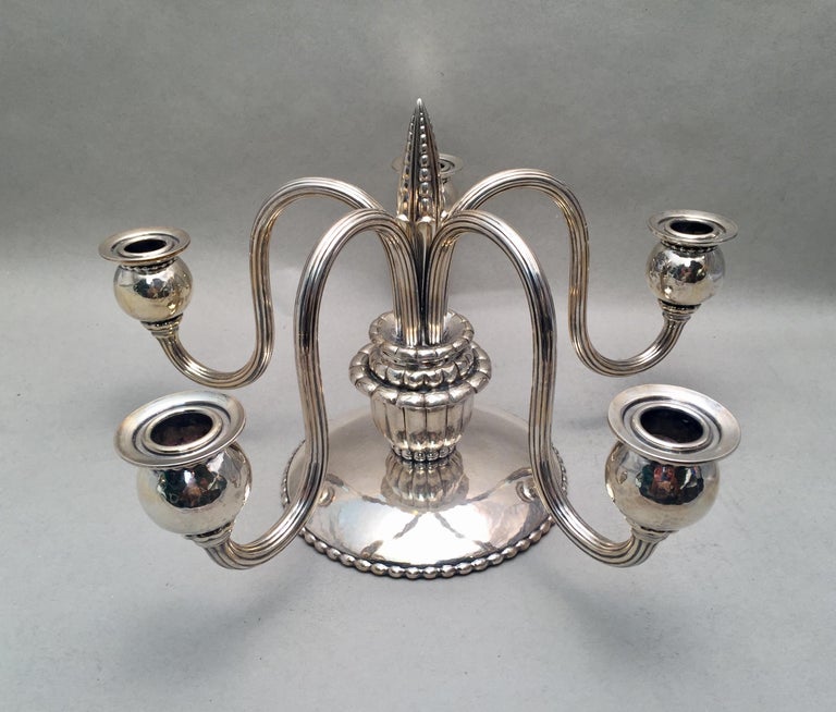 A beautiful pair of five light German .800 silver candelabras by Louis Werner. Designed with waved arms going up and then down. Hand hammered bobeches and base. Oval beading going around parameter of base and beaded finial. Similar to the Jensen