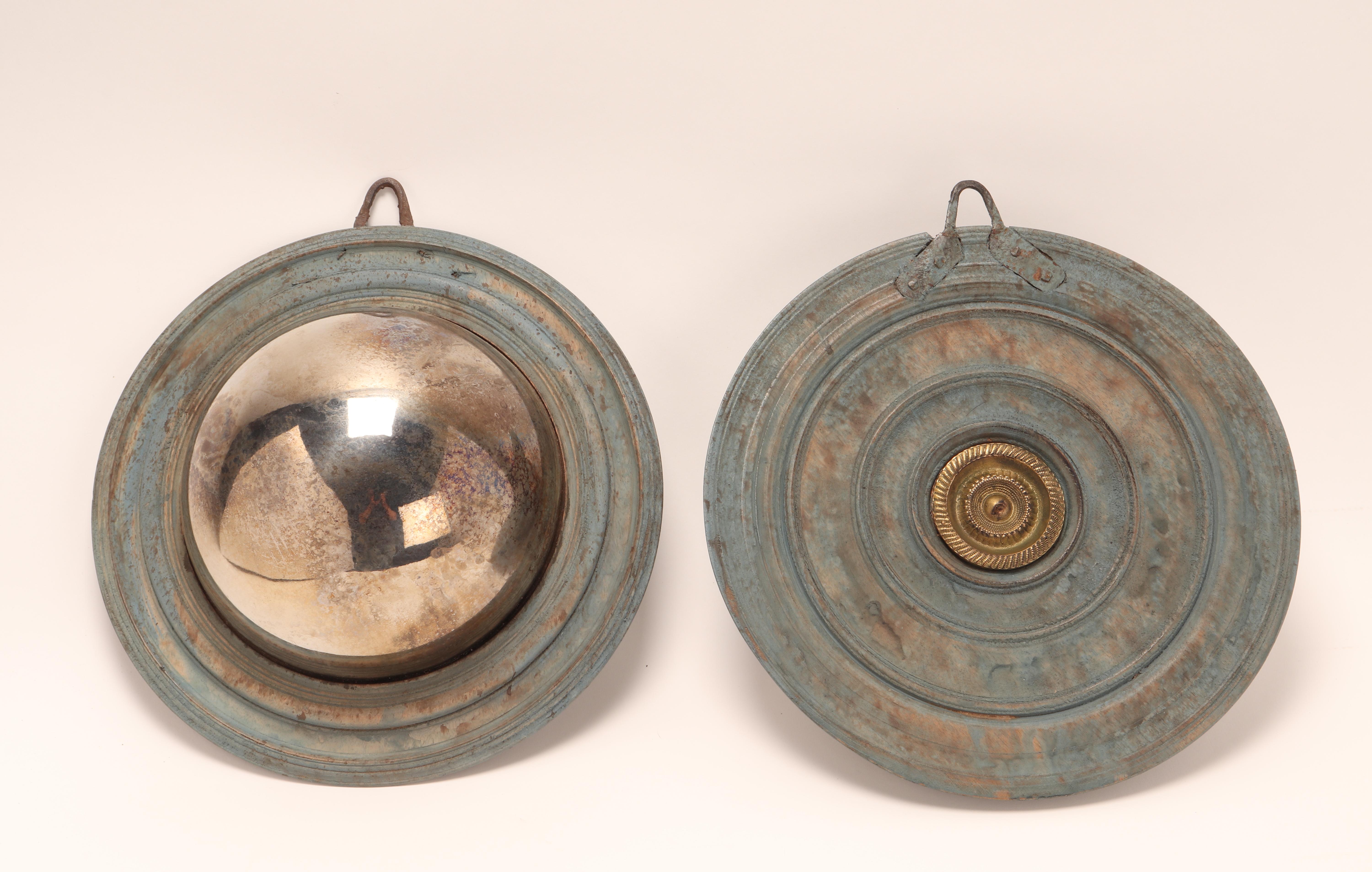 A pair of metal mirrors. These convex mirrors were called “witch mirrors” because they were believed to have magic powers, such as visually confusing witches if introduced into the home. In reality, placed in front of a window or door, they cast