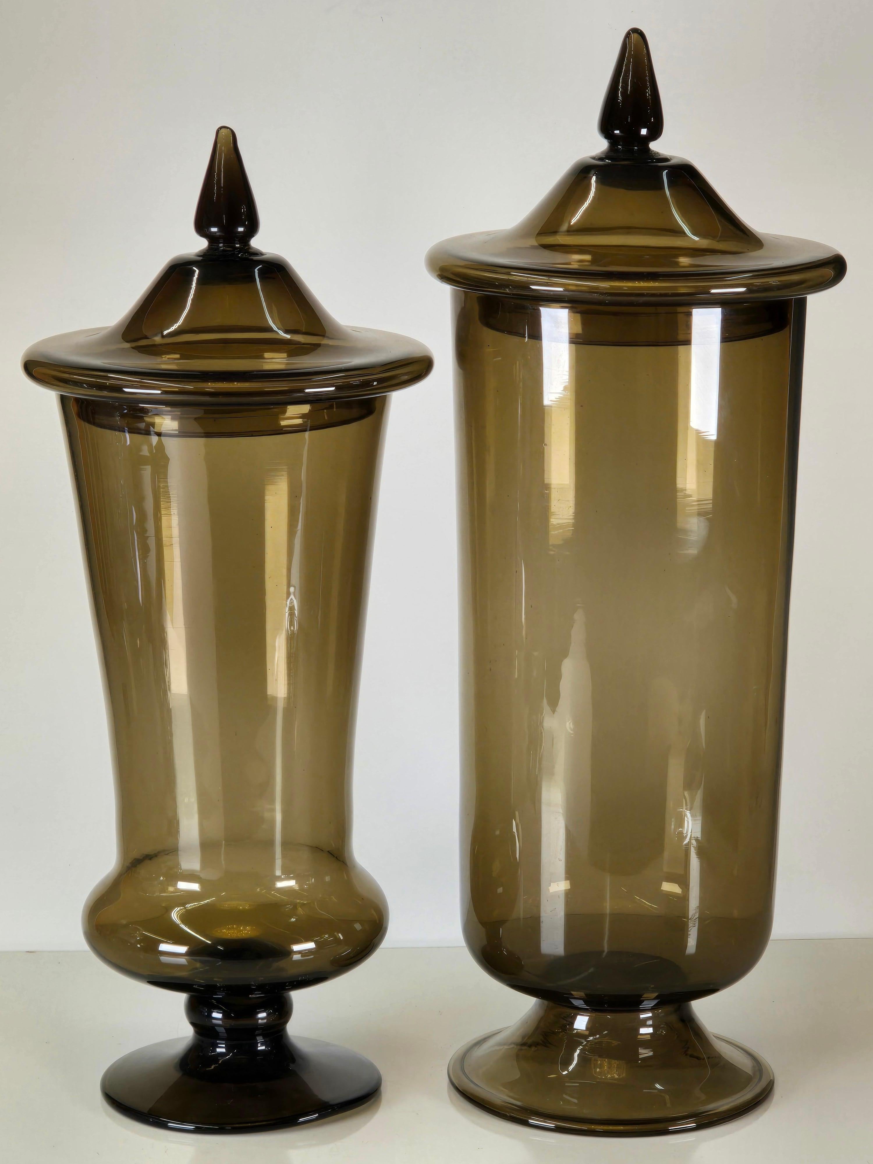 Pair of coordinated blown glass apothecary jars by Empoli of Italy circa 1950.  These are similar to the ones by Paolo Venini, and are even sometimes attributed to Gio Ponti.   A beautiful smokey grey color they're two different heights meant to be