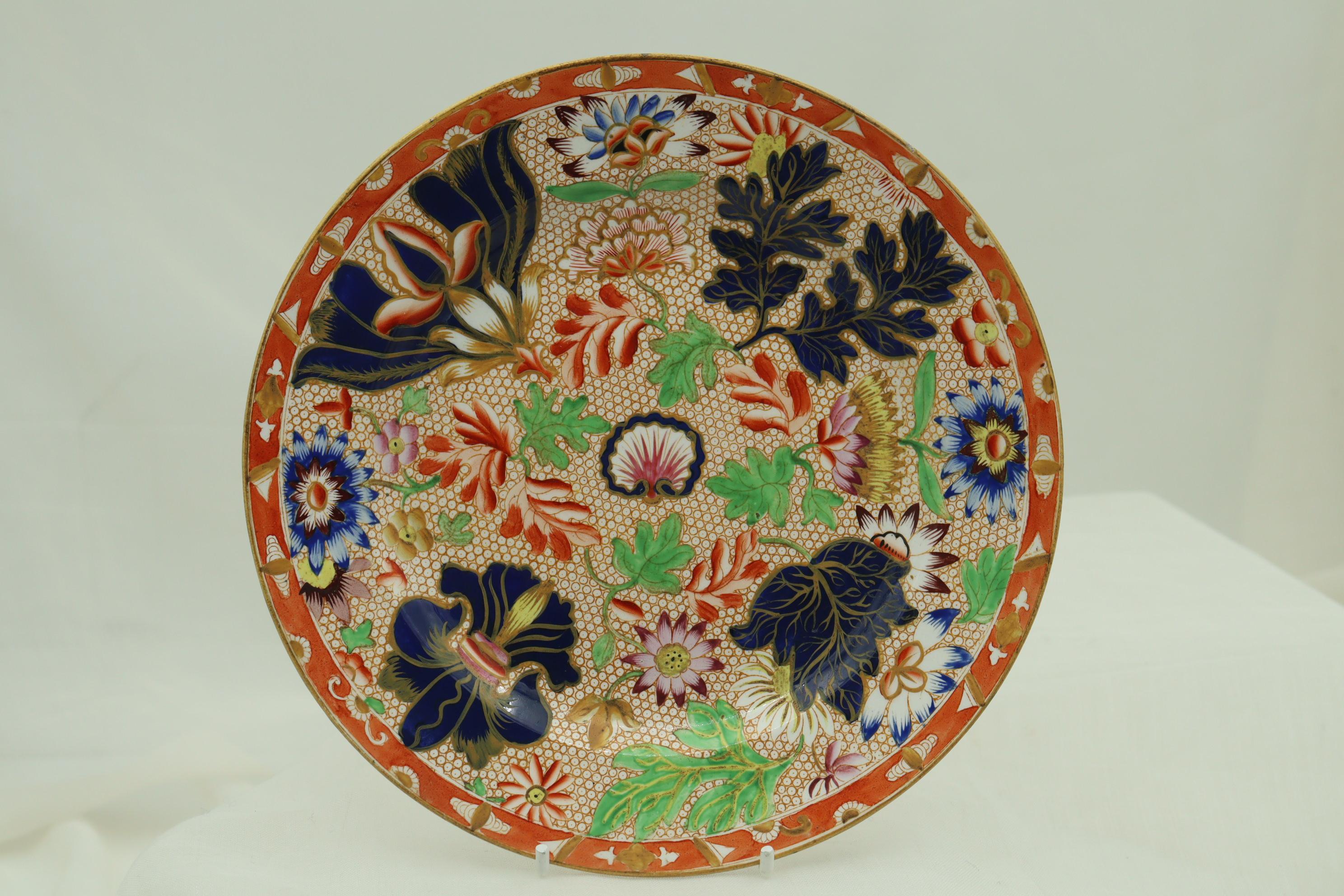 This pair of Copeland & Garrett plates are decorated with an asymmetrical transfer print of an assortment of exotic hand coloured flowers and foliage surrounding a central scallop shell, all on a net ground. The pattern is number 1994, which was