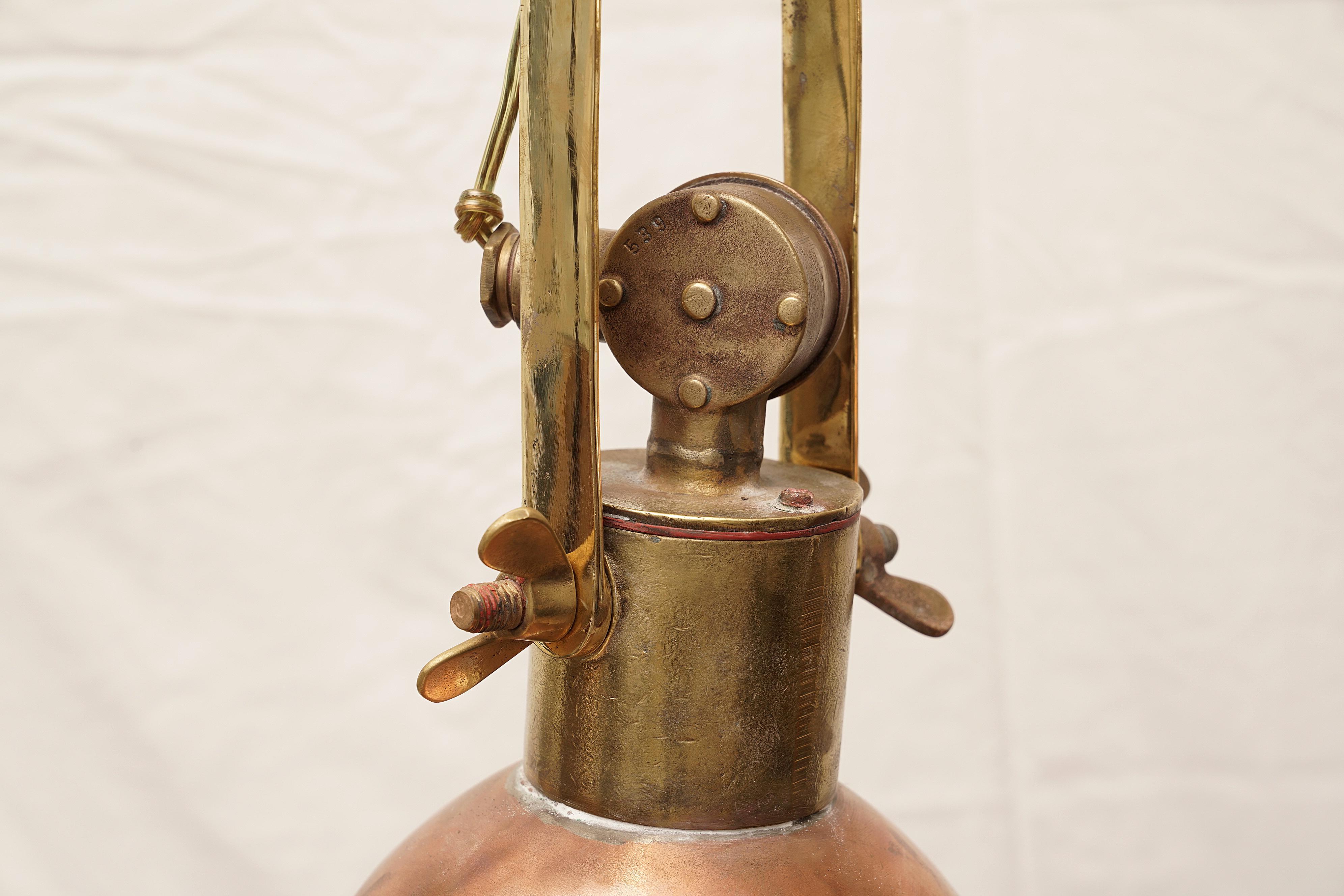 This pair of pendant lights are more like sisters than twins. Two copper and brass ship's deck lights originally used to load and unload cargo at night, circa 1970s. They have been rewired for American use. The tops, below the brackets are slightly