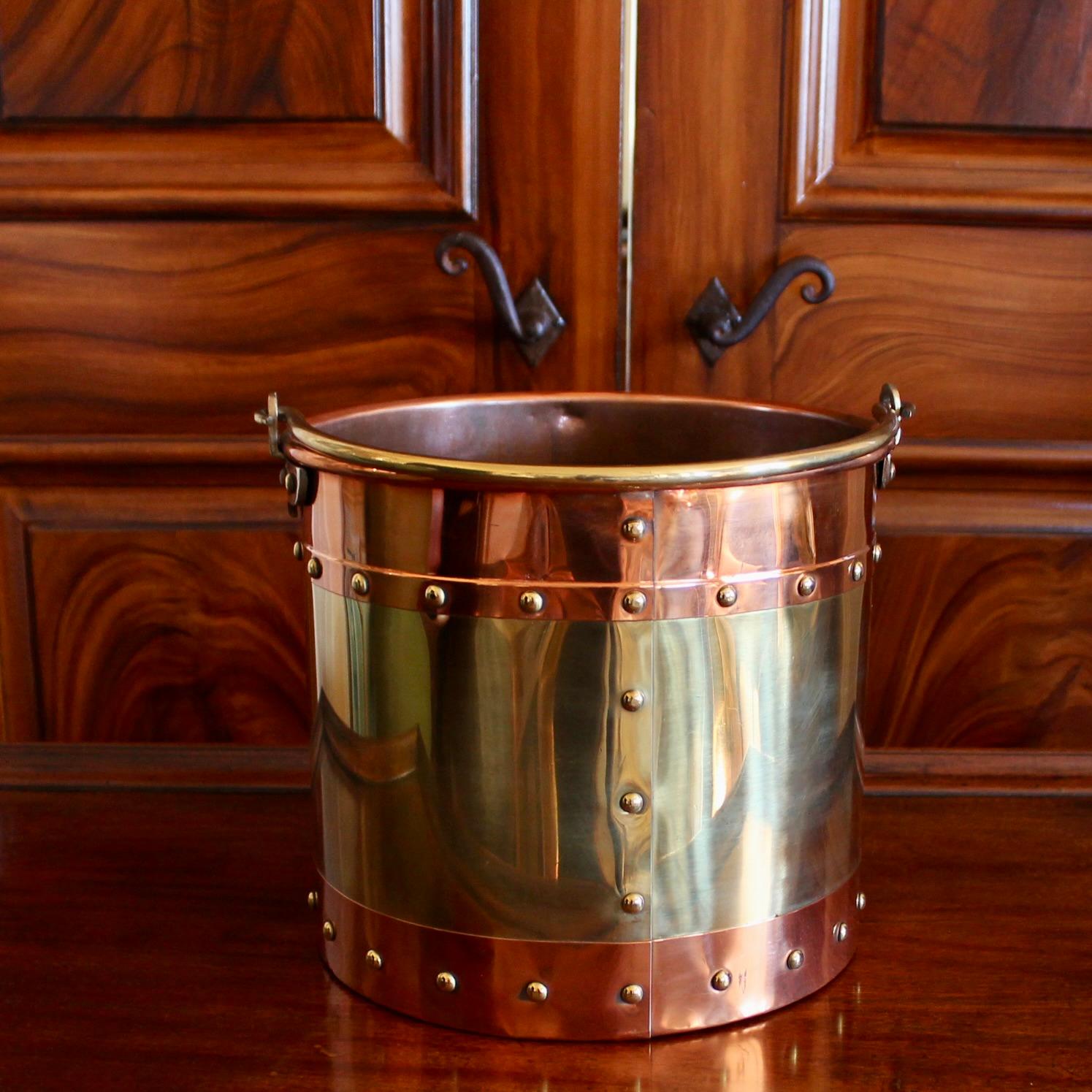 Substantial brass fireplace buckets banded top and bottom with copper, and attractively studded along the seams. A great English look, suitable for kindling, fancy wastebaskets, etc. Polished. Some irregularities as made, variations to patina.