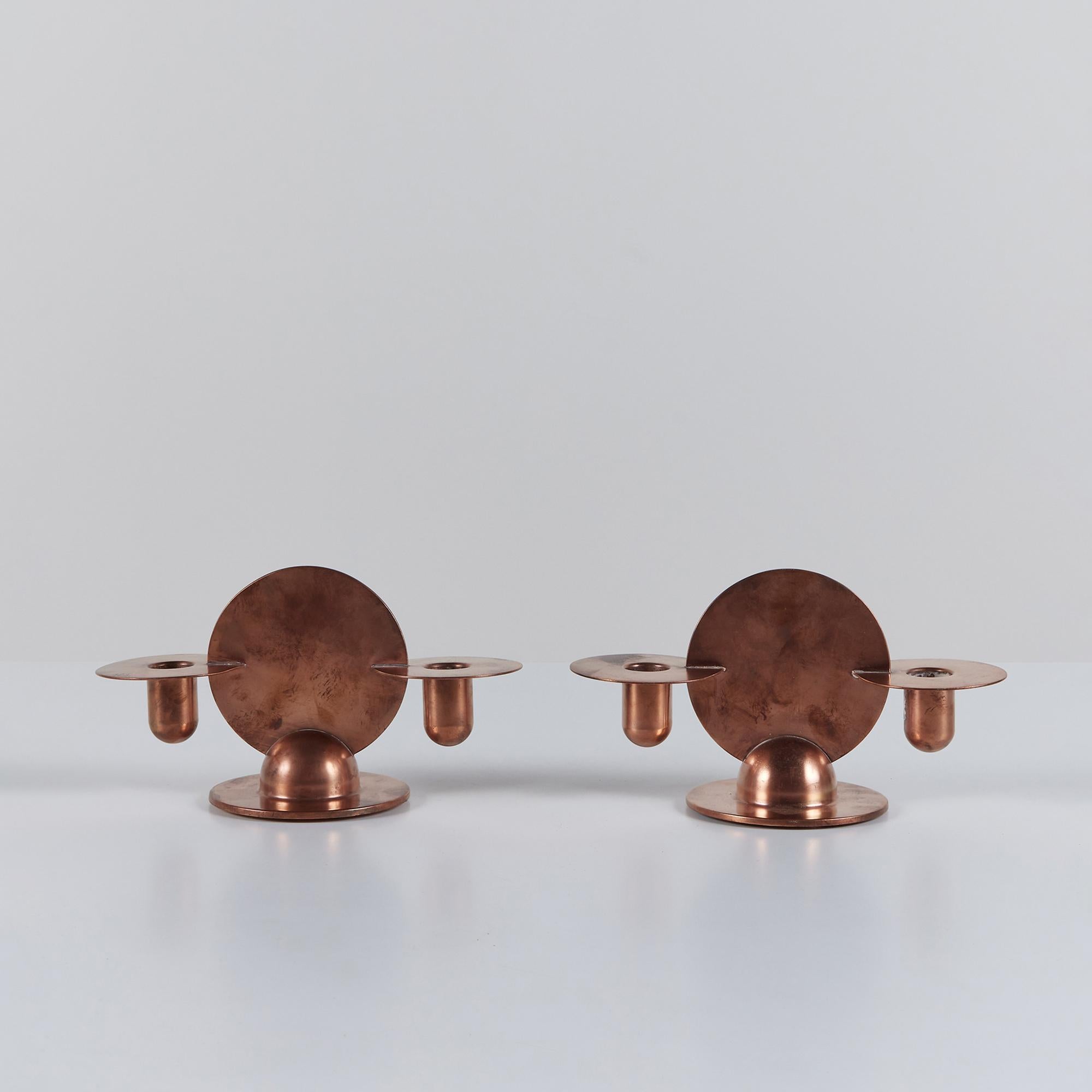 Pair of solid copper candle holders by Walter von Nessen for Chase, c.1930s, USA. The pair of Art Deco candle sticks feature geometric circles and spheres. The minimalist design has one centric circle and two circular floating candle stick holders.