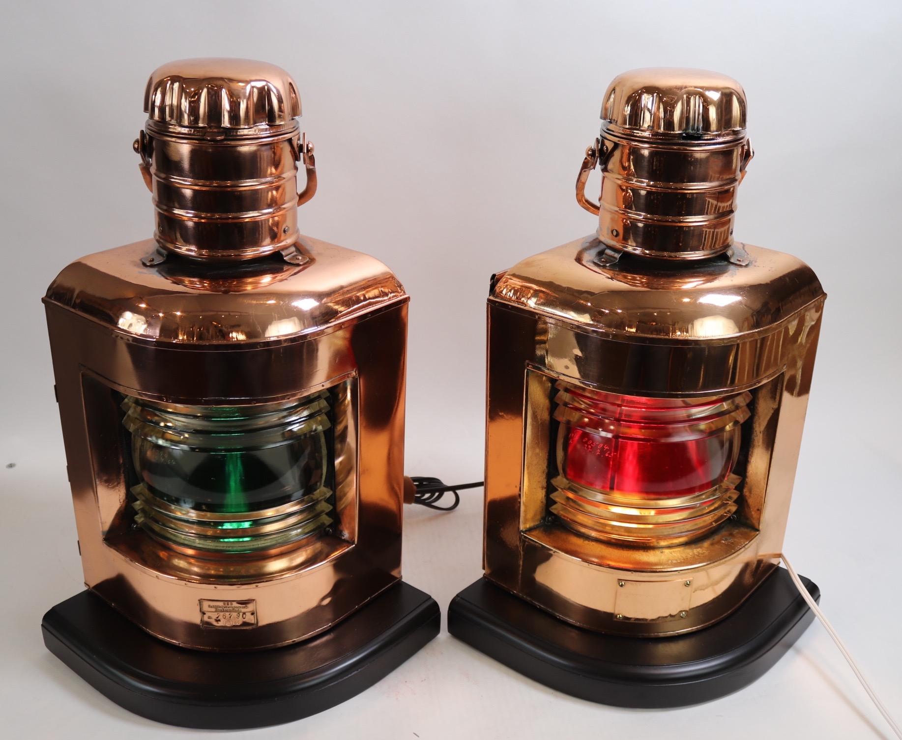Pair of highly polished and lacquered port and starboard ships lanterns with glass fresnel lenses, vented tops, mounted to thick wood bases and new wiring and sockets for home display. Weight is 32 pounds.