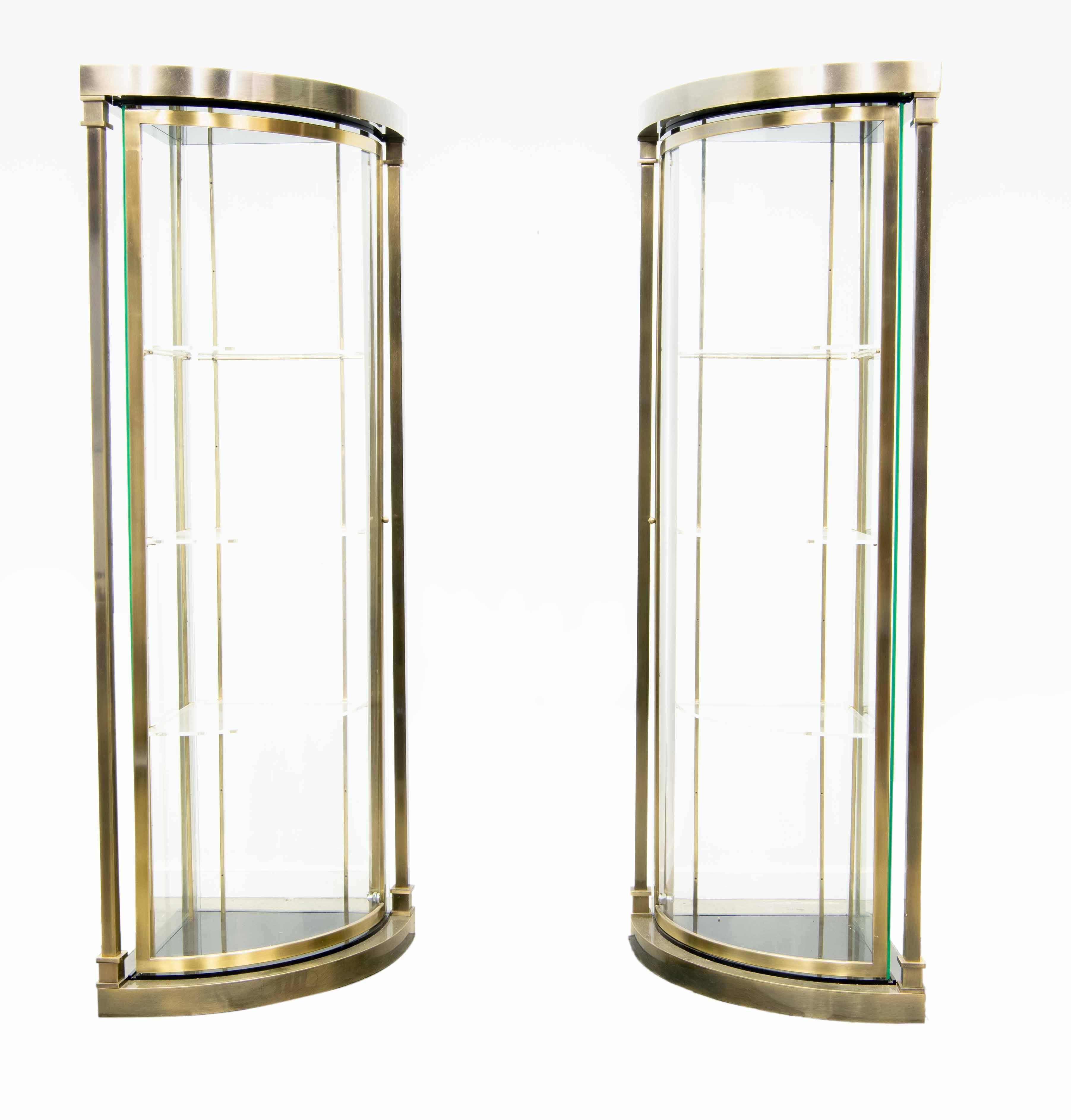 This pair is made of gilt chromed metal, plexiglass and glass. The cabinets were made circa 1980 by Belgo Chrome in Belgium. Their structure is a 23-karat gold plated metal structure. The front door is made of a chromed frame with bent plexiglass.