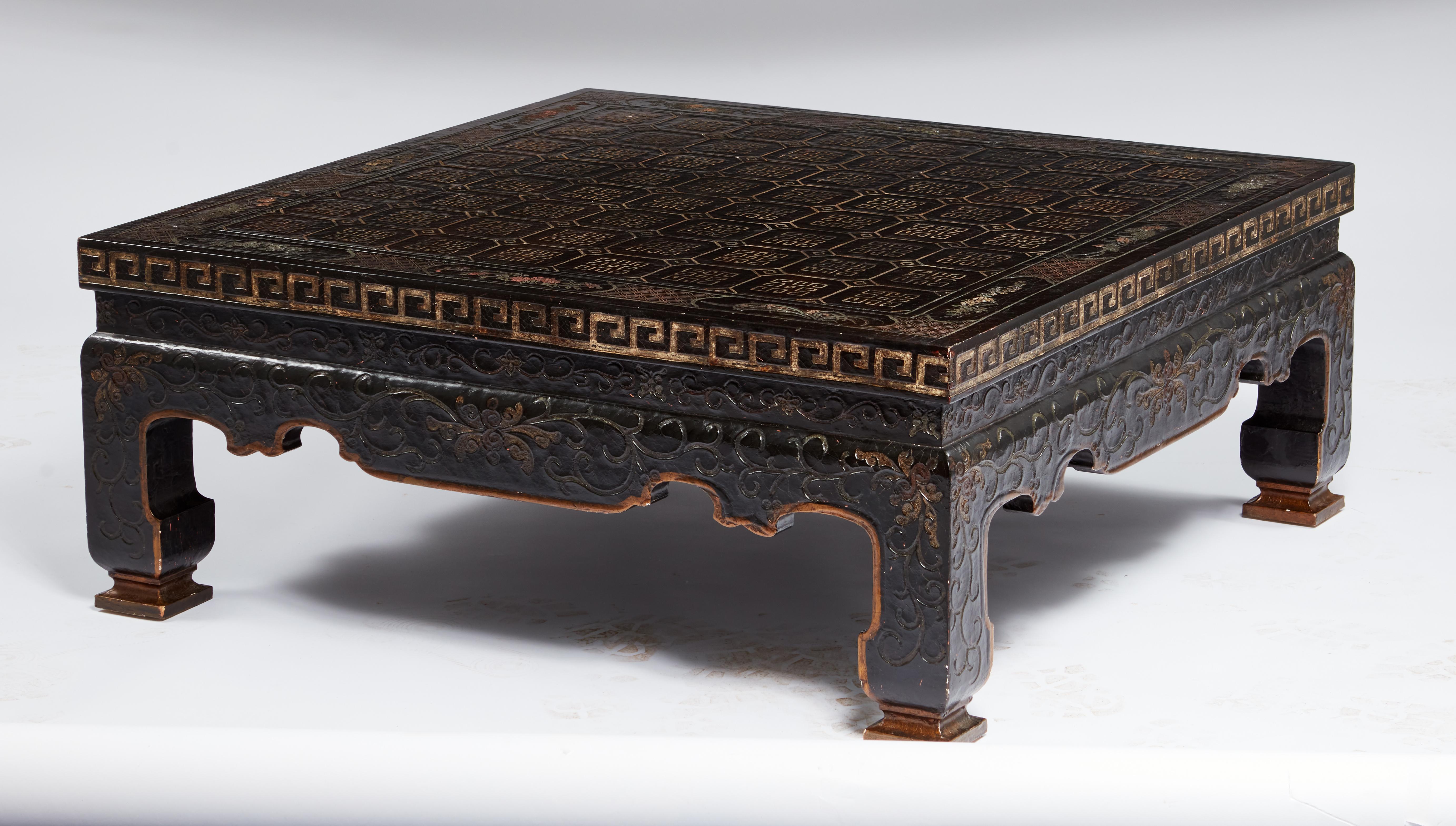 Executed in the manner of a coromandel screen and having a traditional Asian form,  these elegant tables are chinoiserie decorated, comprising a black lacquered base, with an inscribed design finished in poly chrome and gilt-wood.