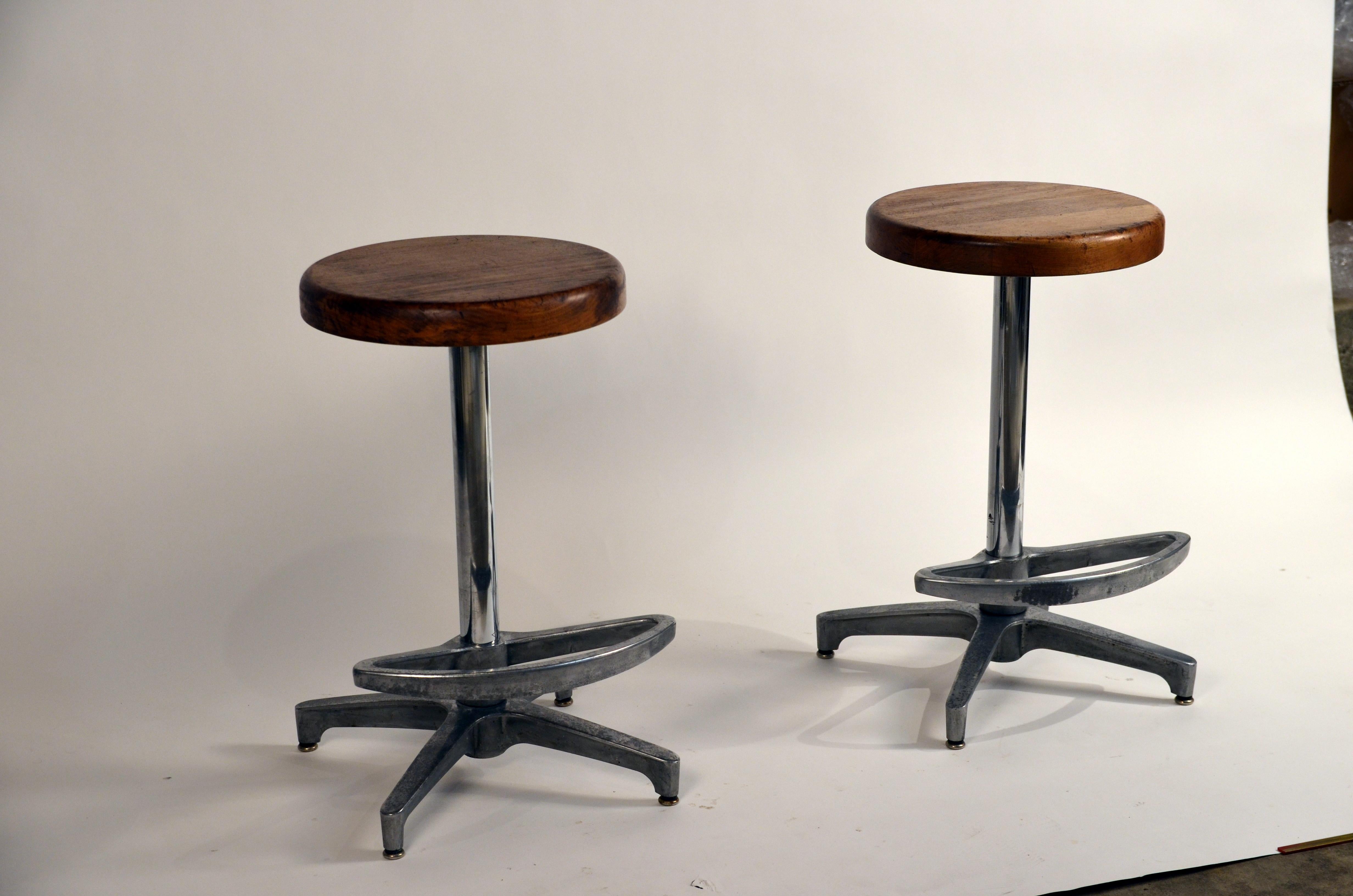 Pair of counter height swiveling bar stools. The footrests swivel as well, or can be locked into position. Great patina to the metal bases and the wood seats.

The seats are 14 in. diameter and 2 in. thick.