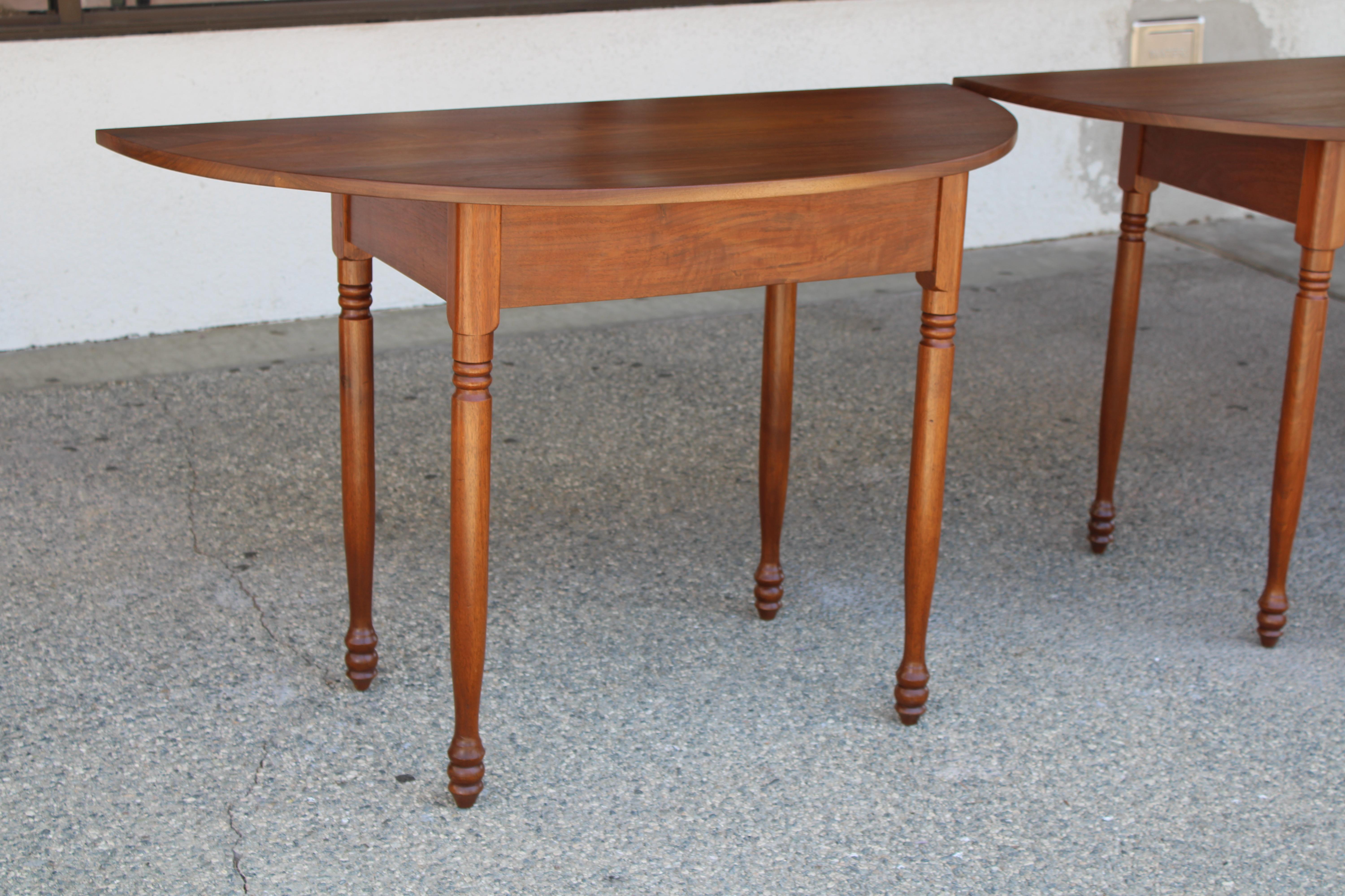 A pair of country console tables, each having a demi-lune top, above tapered legs.  These tables are solid wood.  Tables measure 48
