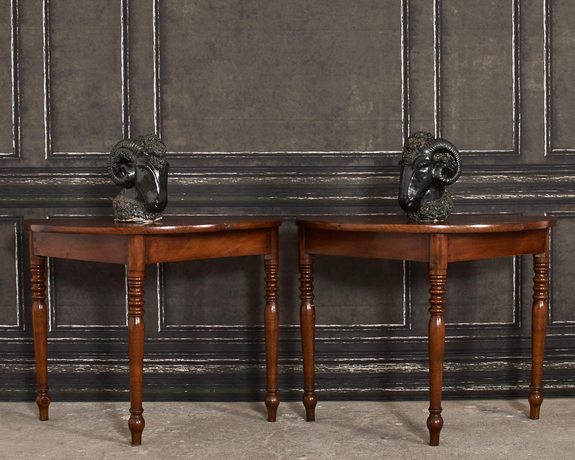 19th century gorgeous pair of country English provincial demi-lune console tables crafted from walnut. Constructed from wood dowel peg joinery having demilune shaped tops above triangular shaped aprons. Originally ends of a banquet table the pair