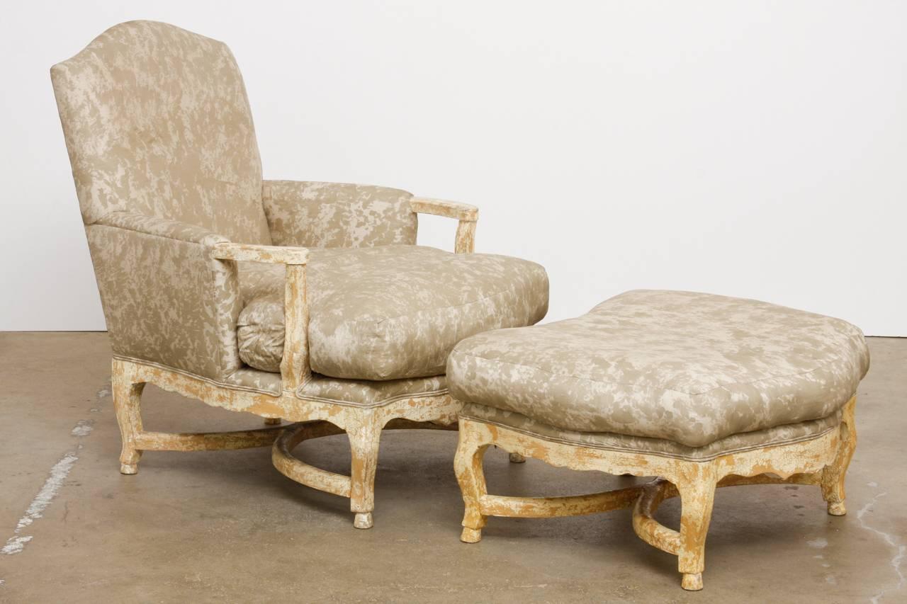 Grand pair of Bergere armchairs with a matching ottoman featuring a distressed scraped paint finish. These bespoke armchairs are made with generous proportions having bowed fronts and serpentine arms. Supported by short cabriole legs with X-form