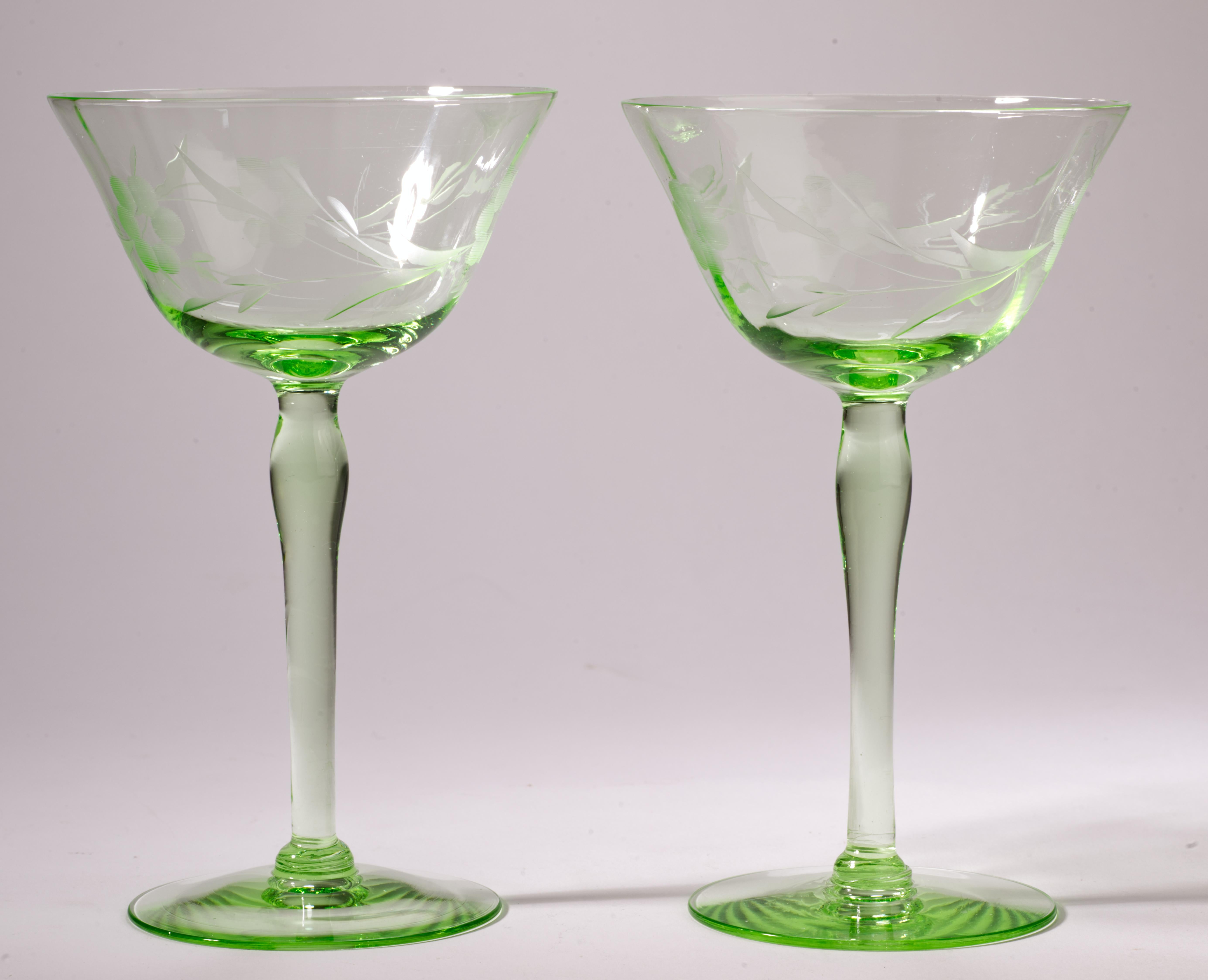 Vintage Mid-Century Modern coupe glasses were made of uranium green glass that almost fades to clear in thinnest area around the rims. The glasses are decorated with abstract etched flower decor; they glow intensely in UV light.