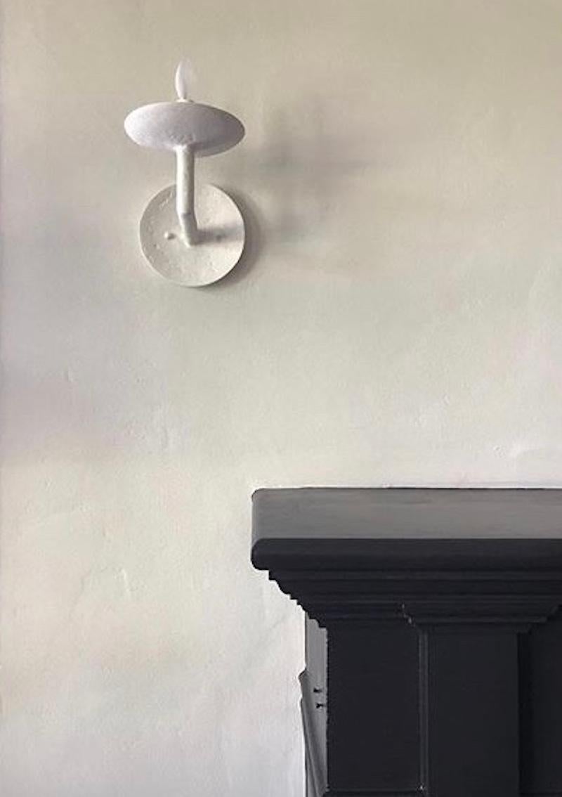 Two plaster of Paris wall sconces which complement our chandelier of the same design. The minimalist light has an organic plaster finish. Lights uses one candelabra based bulb. Max wattage is 60 per light.