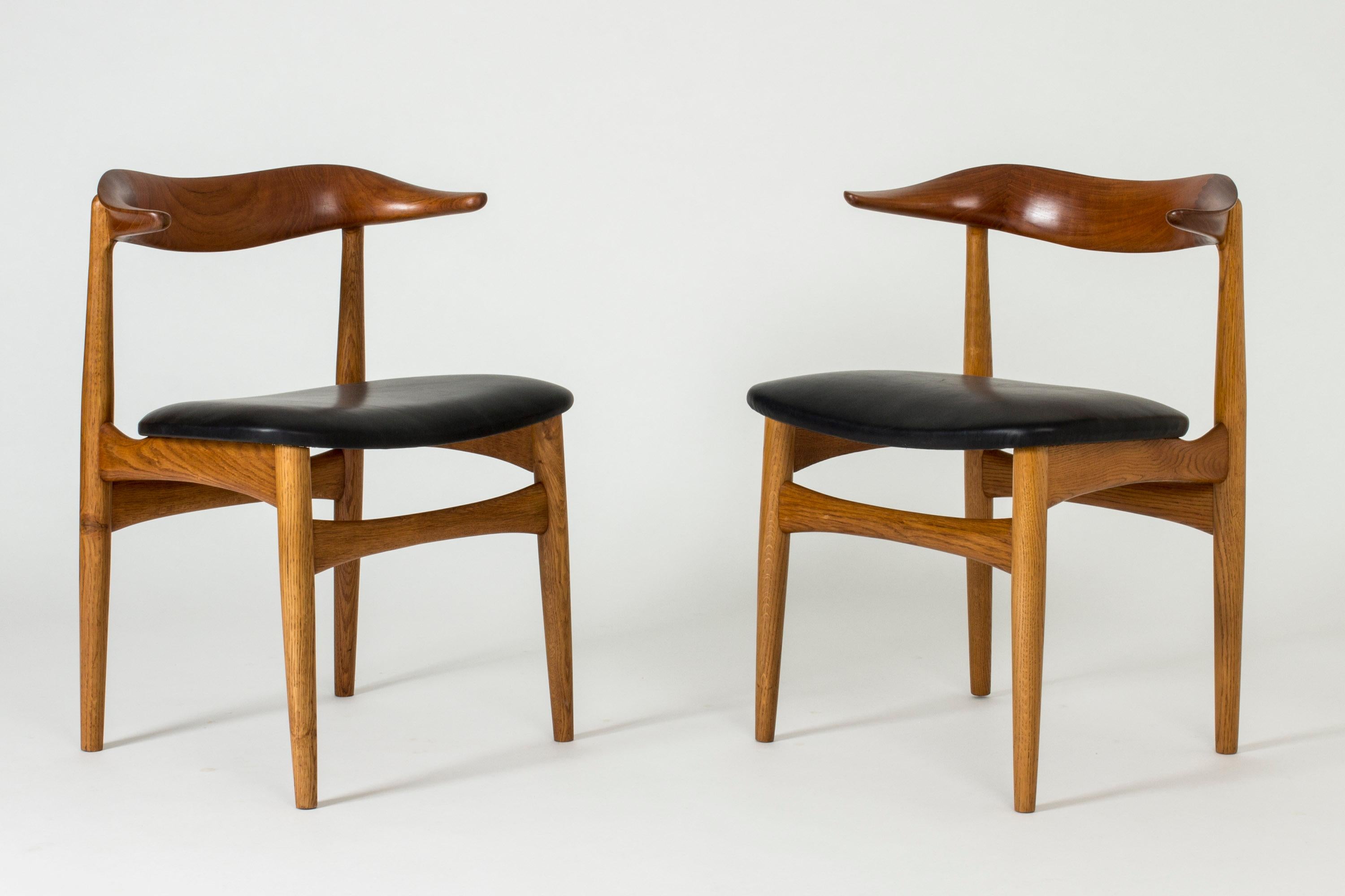 Pair of amazing “Cowhorn” dining or side chairs by Knud Færch, made from teak with black leather seats. Beautifully sculpted backrests in a precise, undulating form.