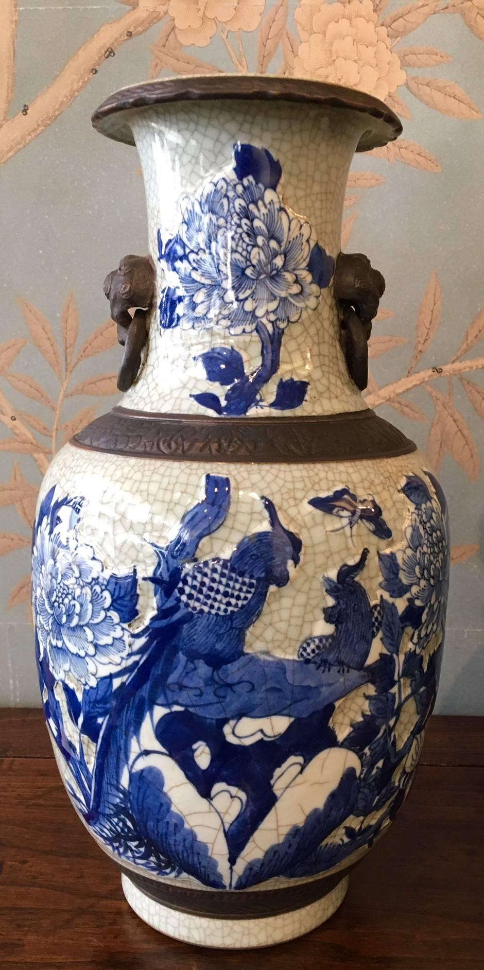 A pair of early 20th century blue and white crackleware vases with faux bronze bands, birds, butterflies and flowers.