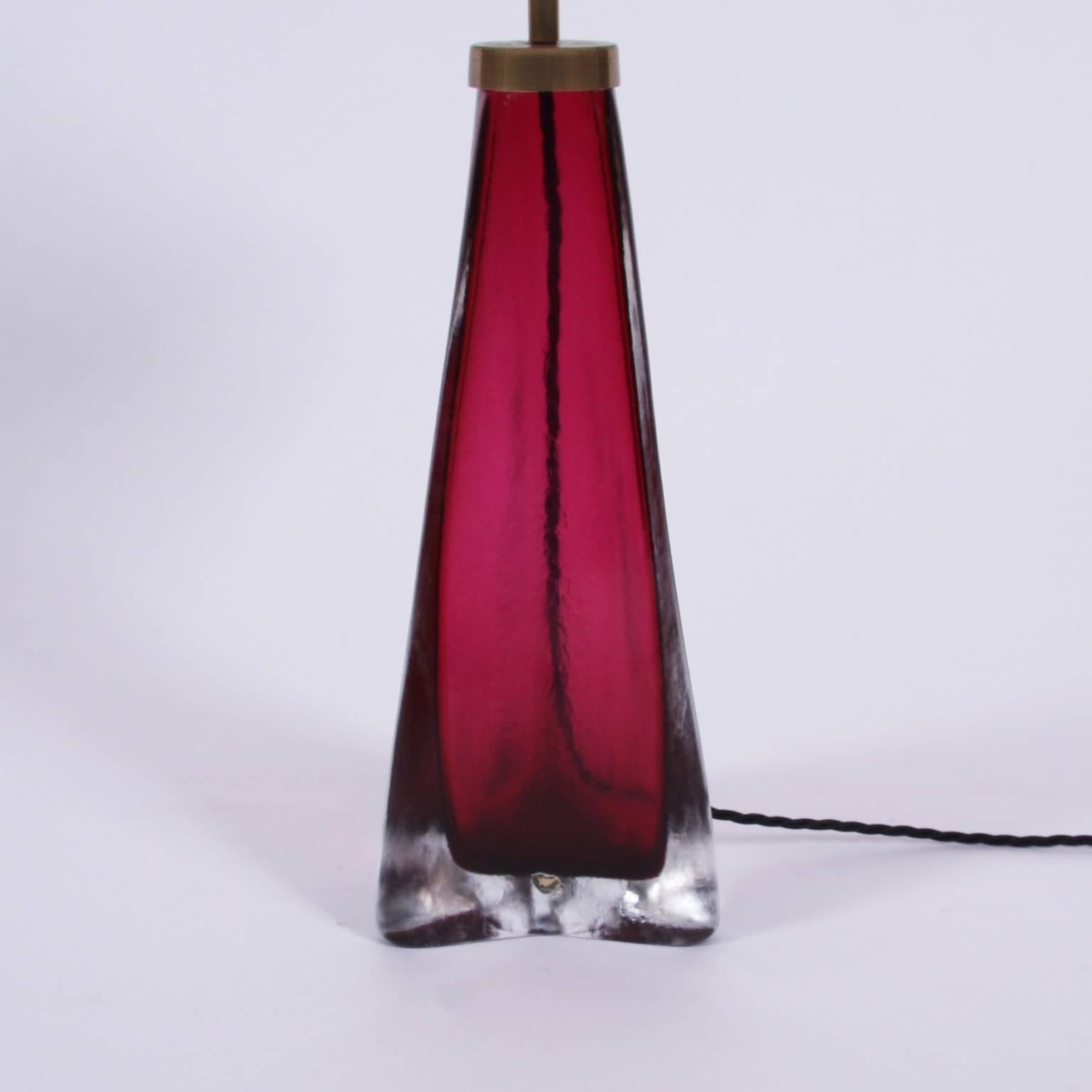 Swedish circa 1950

A pair of glass table lamps, by Orrefors, in a lovely cranberry color with triangular shape. Stamped with maker's name. 

Pictured with bespoke, handmade, shades. 

Rewired and PAT tested.